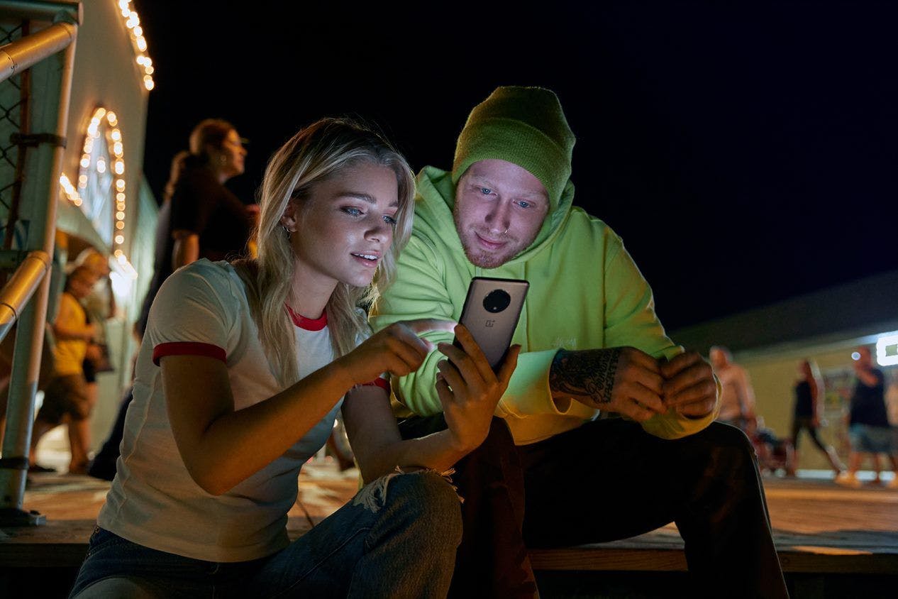 En mand og en kvinde samles ser betagede på den nye OnePlus 7T
