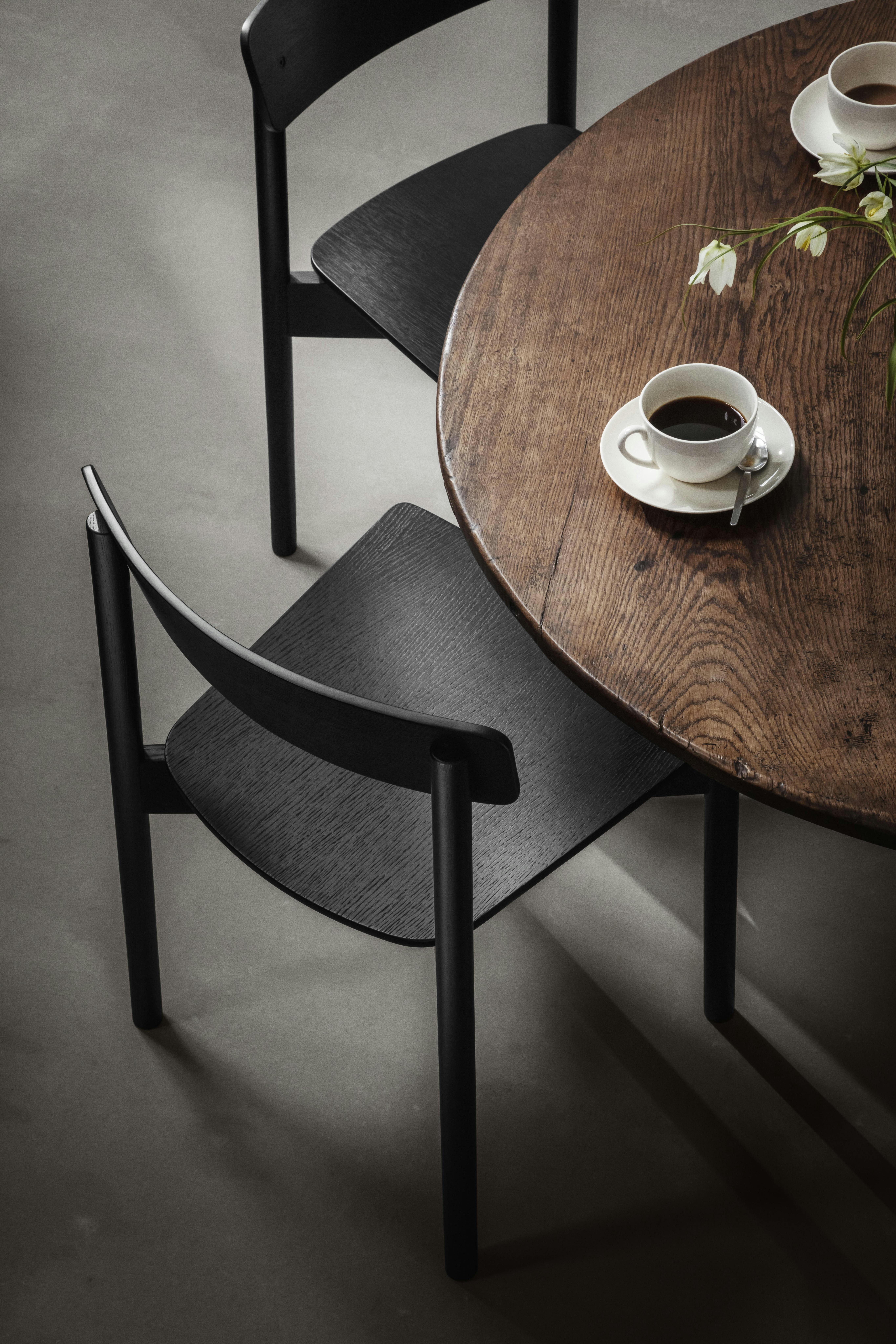 De stoelen van TAKT komen in verschillende kleuren en materialen TAKT stoelen zwart, bruine tafel met koffie