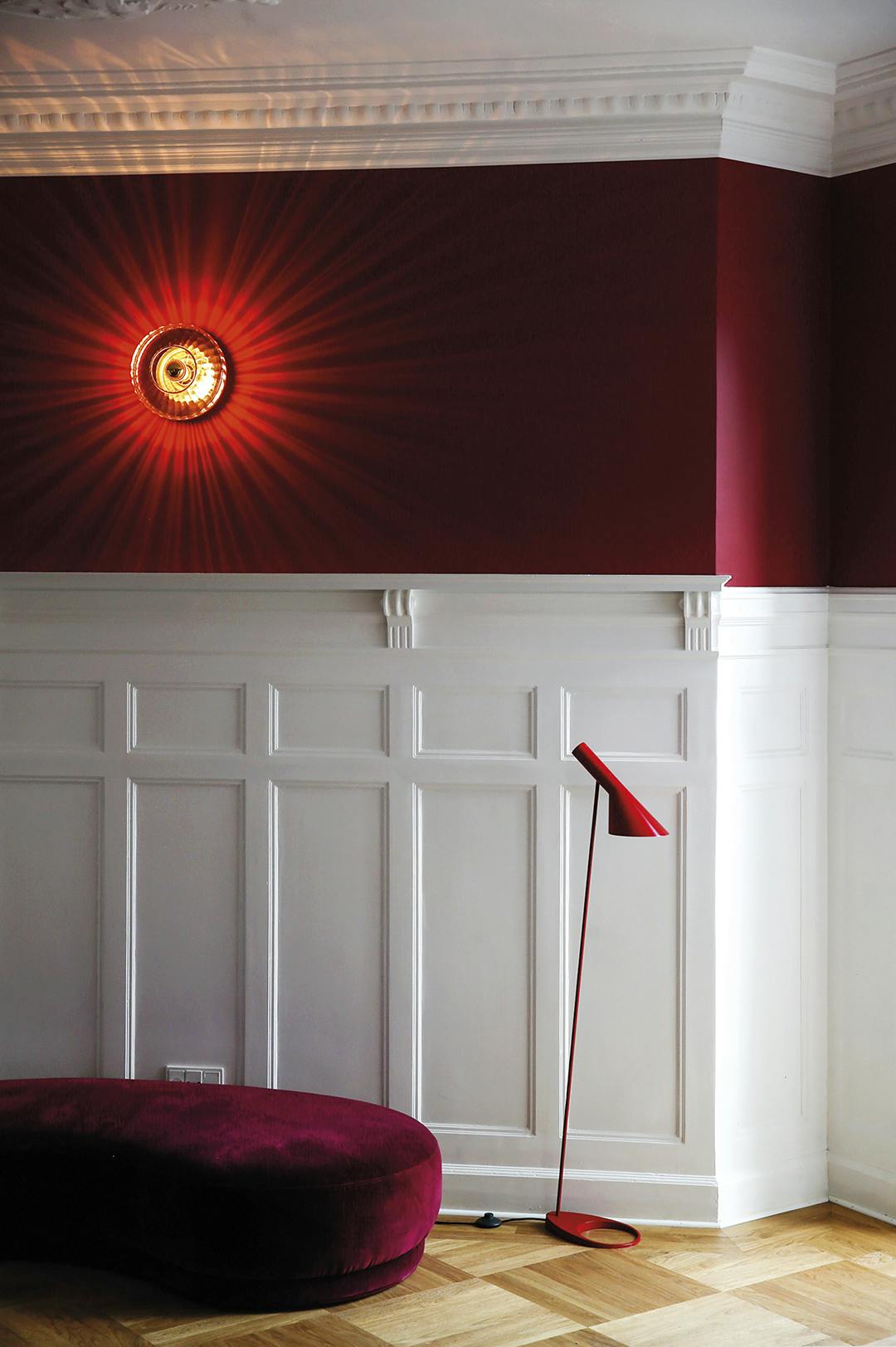 De velours poef van Jotex heeft gezelschap van een rode vloerlamp van Arne Jacobsen van Louis Poulsen en de wandlamp van Design By Us. Jotex poef, Arne Jacobsen lamp voor Louis Poulsen