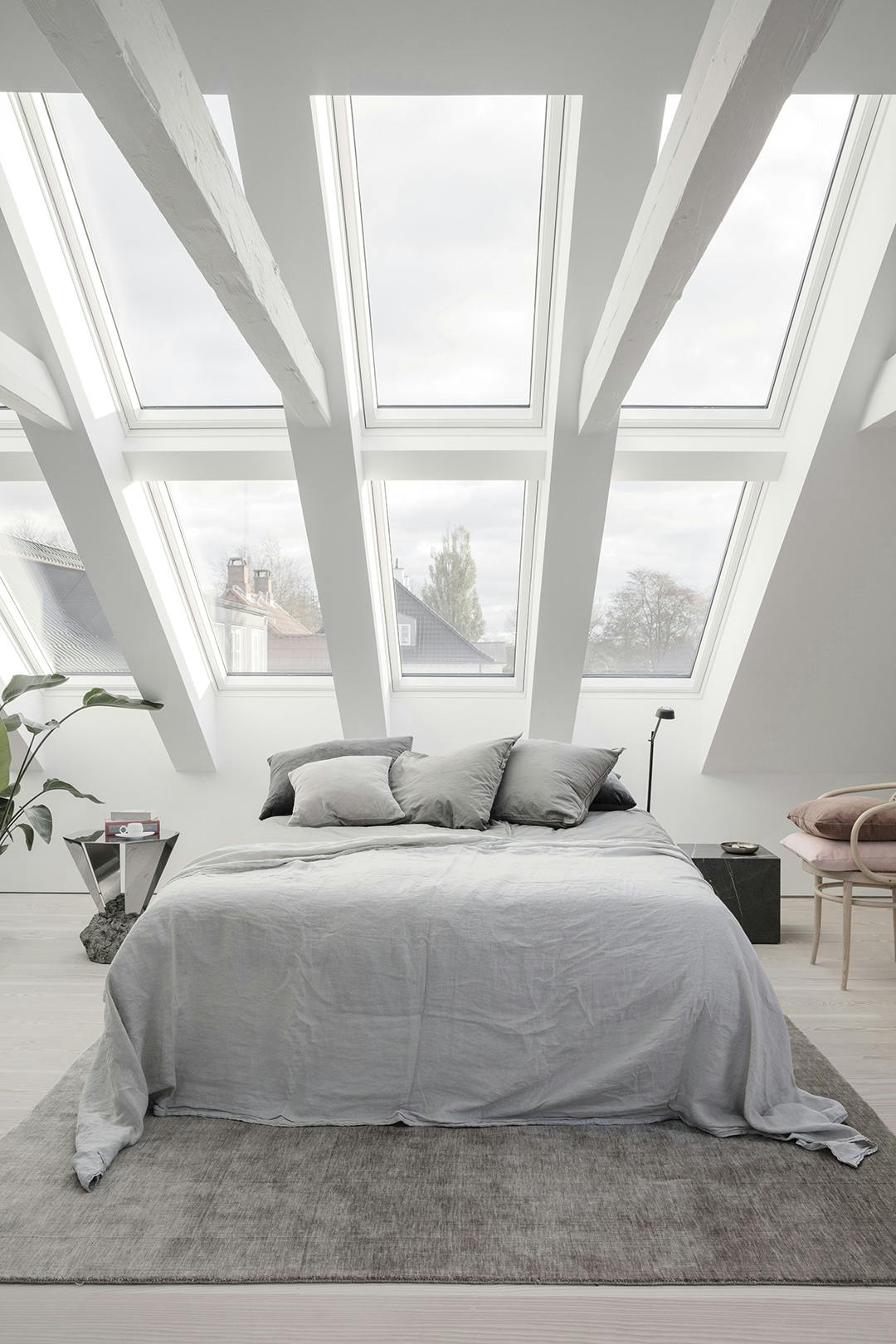 Het vloerkleed van Massimo Copenhagen is van bamboevezel. De bijzondere bijzettafel is ontworpen door Fos. Slaapkamer met dakramen Velux loft