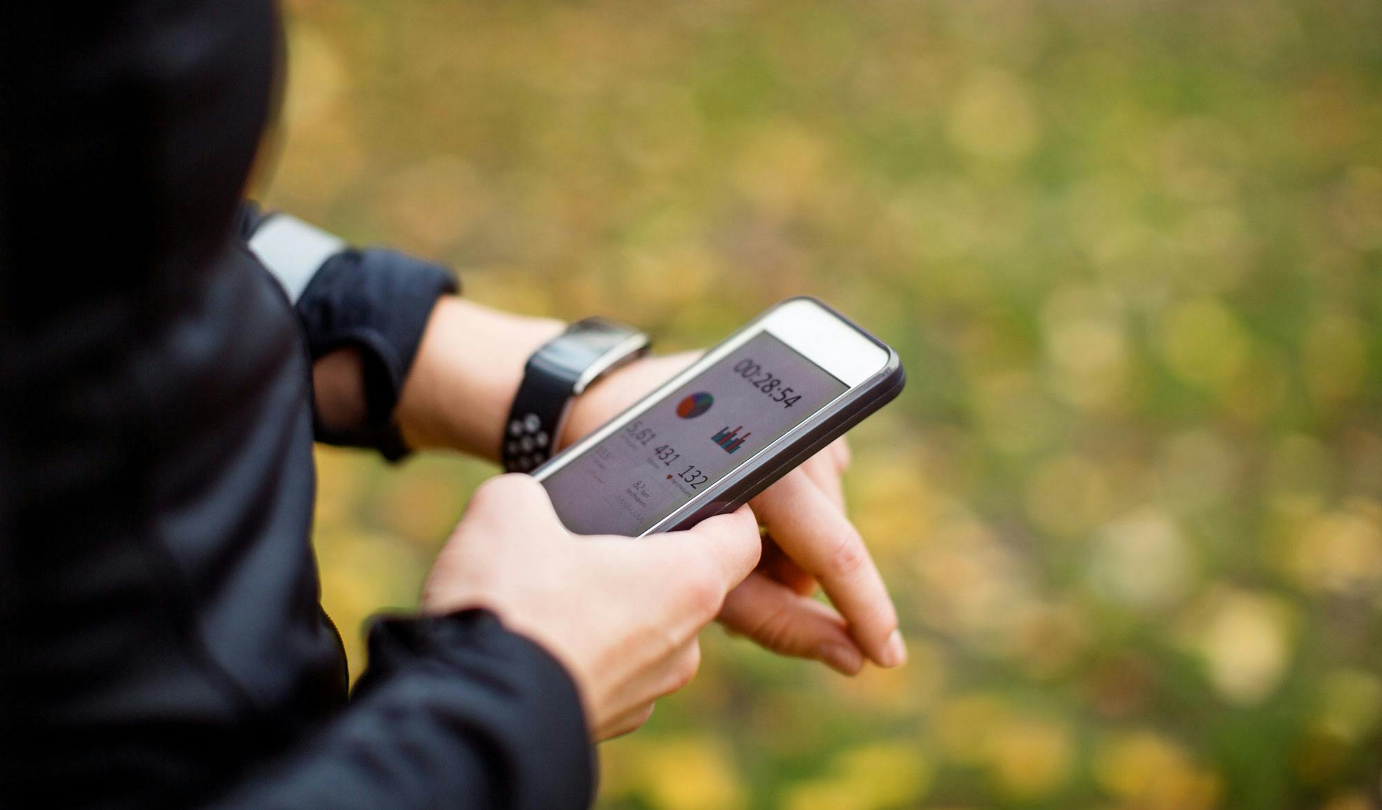 Aktivitetsur med app Kvinde med aktivitetsur og medfølgende app på sin mobil