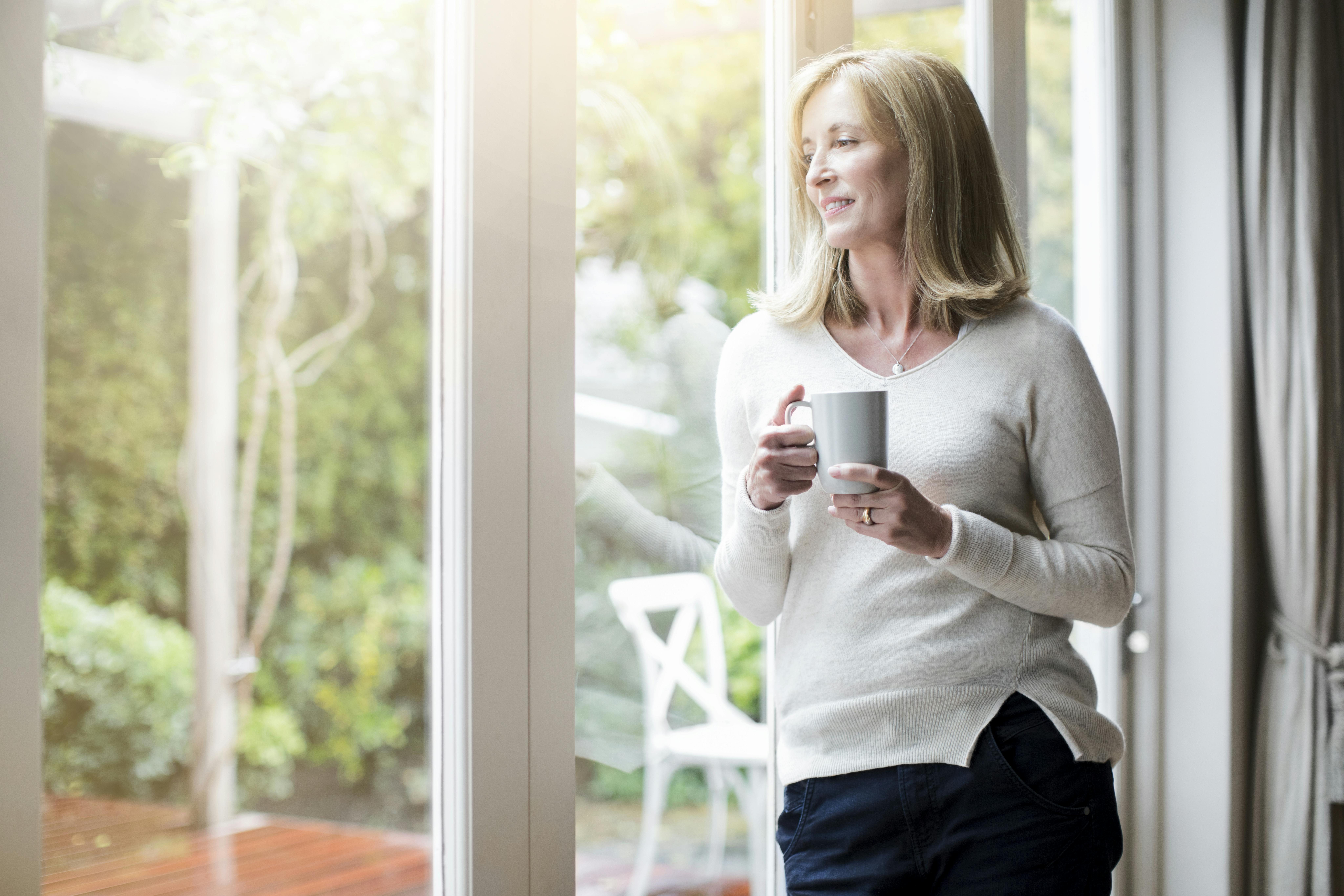 Bruger du også alt for meget tid på at gruble og bekymre dig? Moden kvinde drikker kaffe og kigger ud ad vinduet
