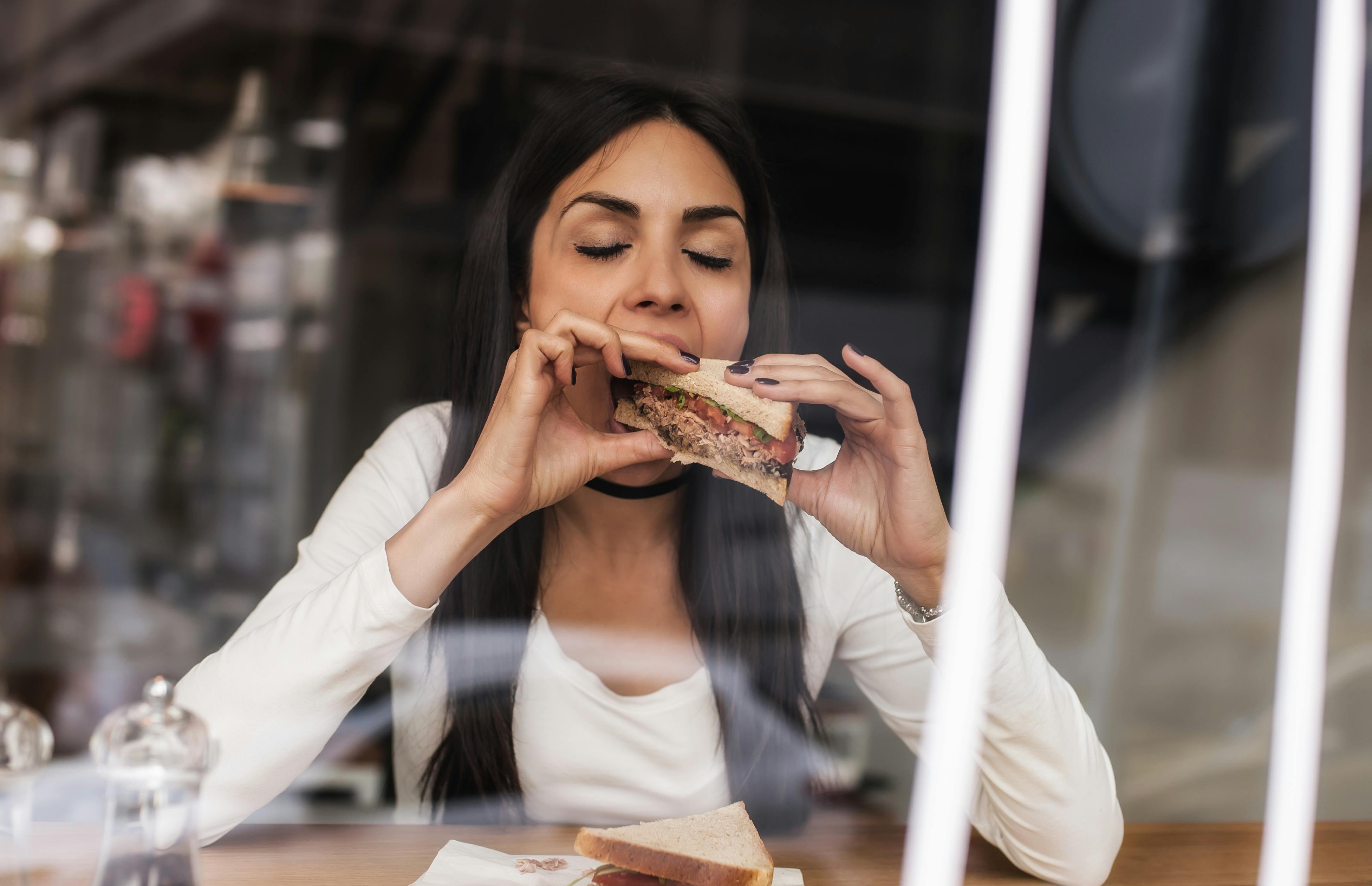 Kulhydrater et gode, hvis du vil undgå dårlig ånde. Kvinde spiser sandwich for at undgå dårlig ånde