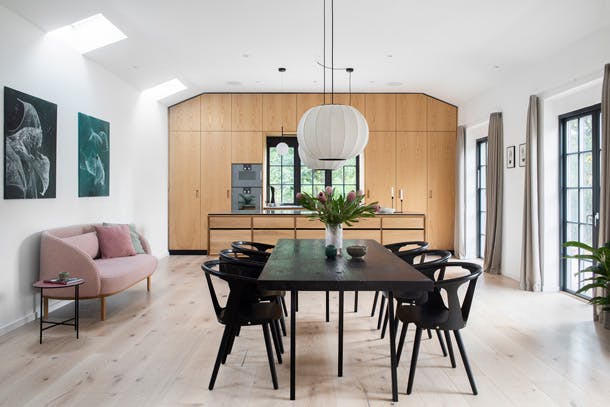 De grote open keuken kreeg een vloer en achterwand van levendig eikenhout. De stoelen zijn van &tradition. keuken van eikenhout met design stoelen