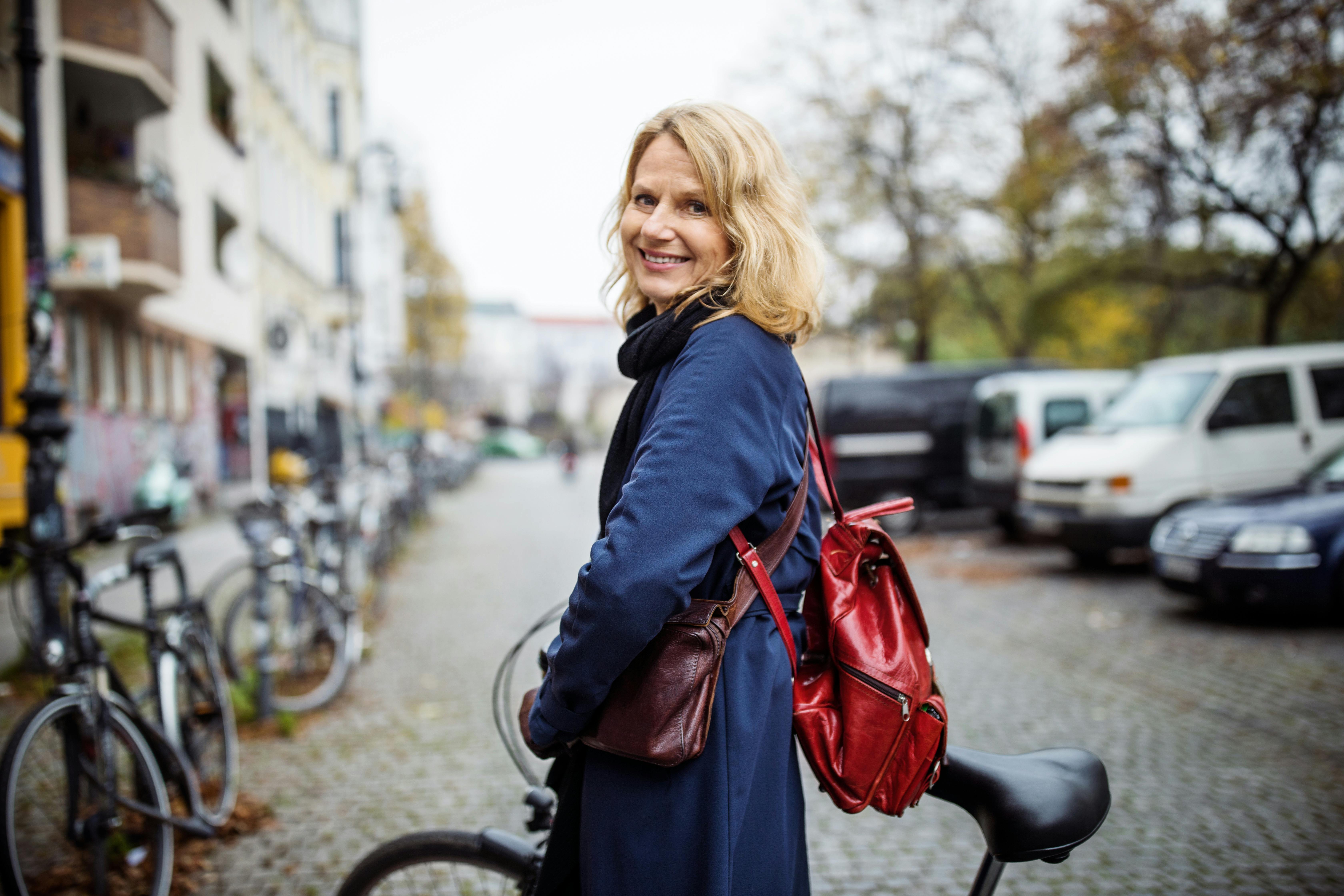Brug din krop som transportmiddel. Og få motion uden at tænke over det. Moden kvinde trækker sin cykel