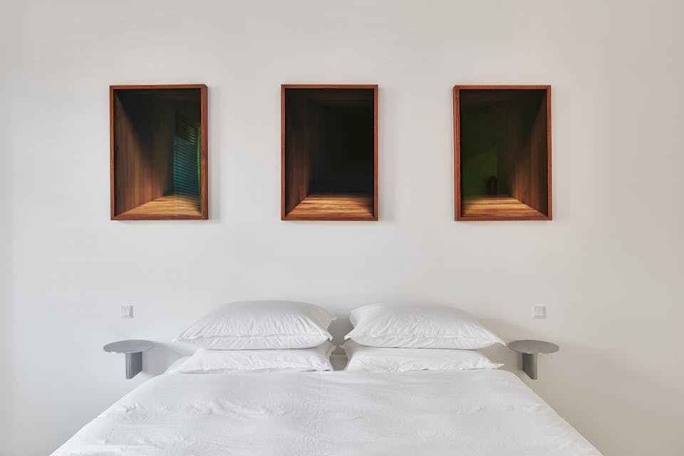 tweepersoonsbed met wit linnen en Theis Wendt kunstwerken