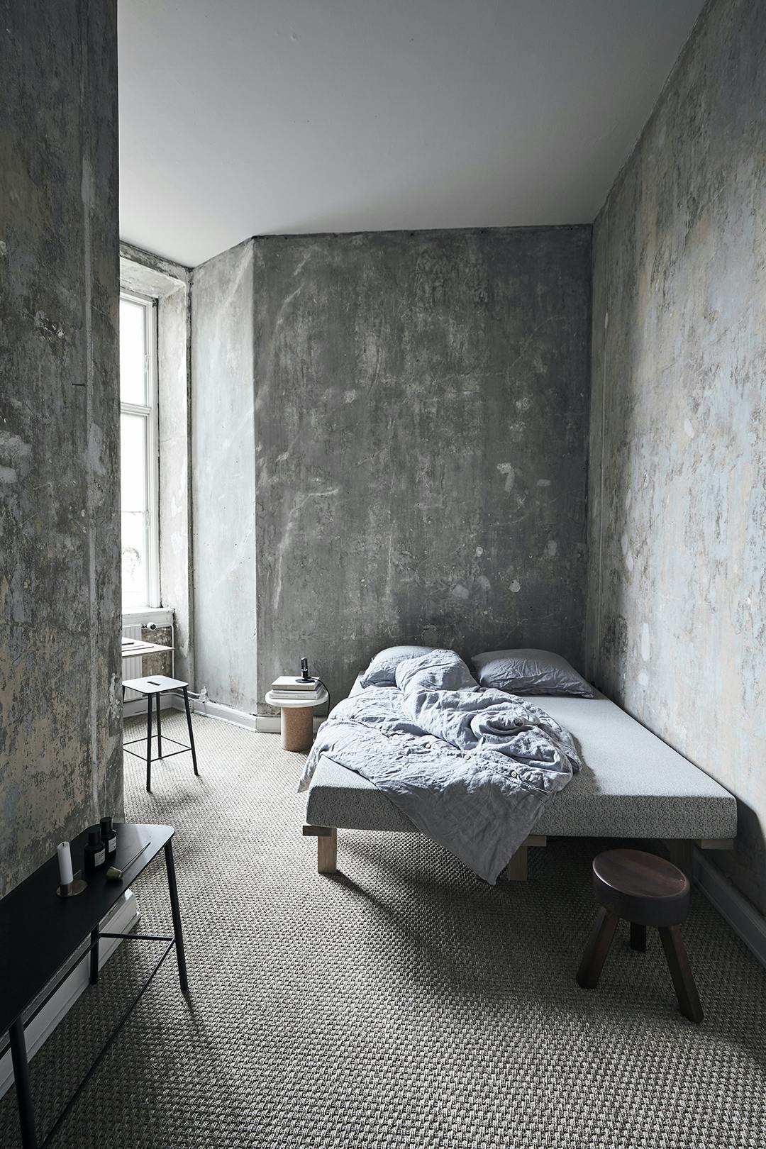 In de slaapkamer contrasteren de ruwe muren met het witte plafond. Op de grond ligt een kamerbreed tapijt van Scandinavian Agent in Seagrass/Sisal. In de slaapkamer contrasteren de ruwe muren met het witte plafond. Op de grond ligt een kamerbreed tapijt van Scandinavian Agent in Seagrass/Sisal.