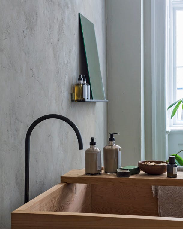 Het bad, de kraan, en de spiegel zijn van Frama. Zelfs de verzorgingsproducten komen van Niels zijn eigen productie. Japans houten bad van Frama in scandinavische badkamer