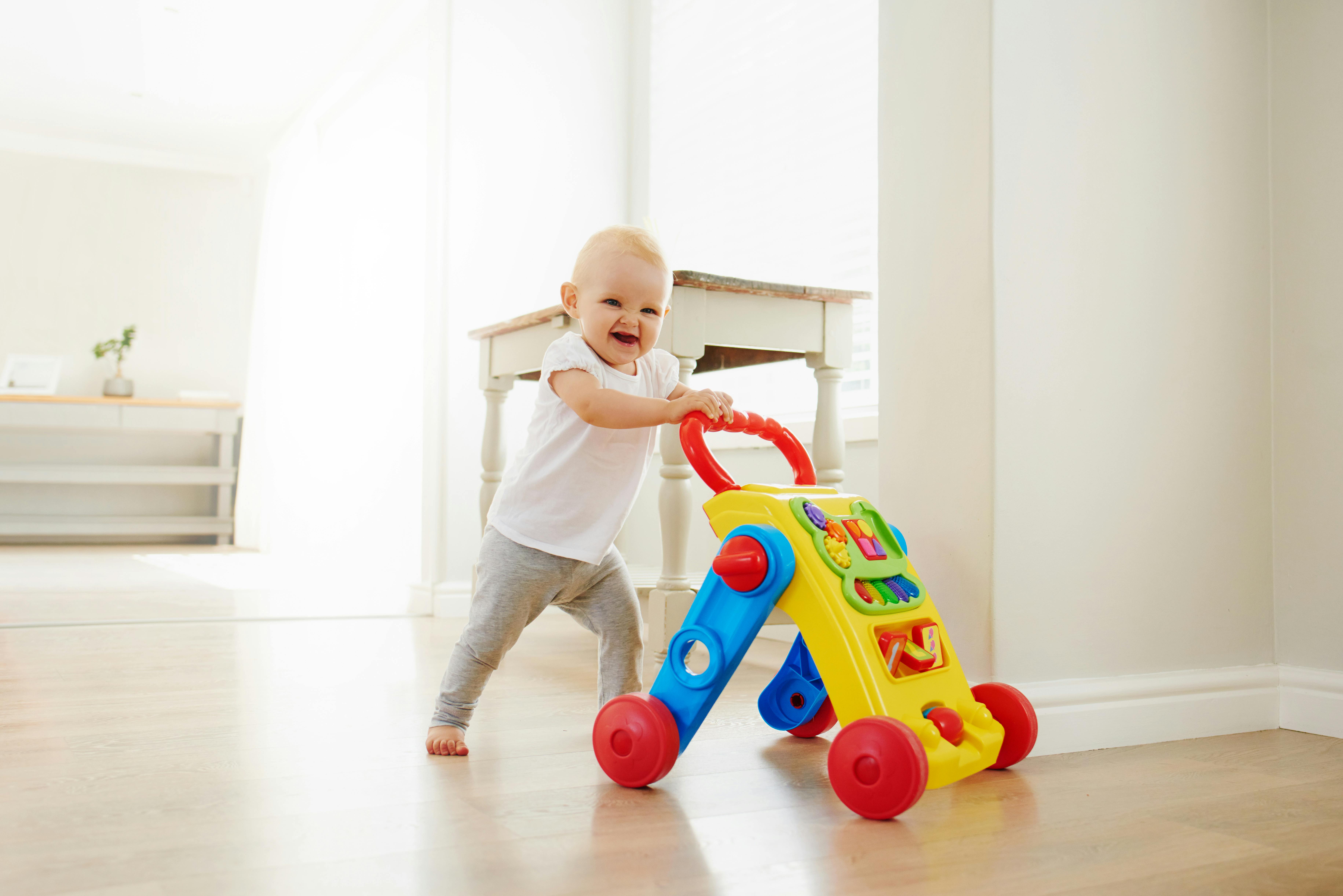 Den frække baby går med en aktivitetsgåvogn. Baby med gåvogn