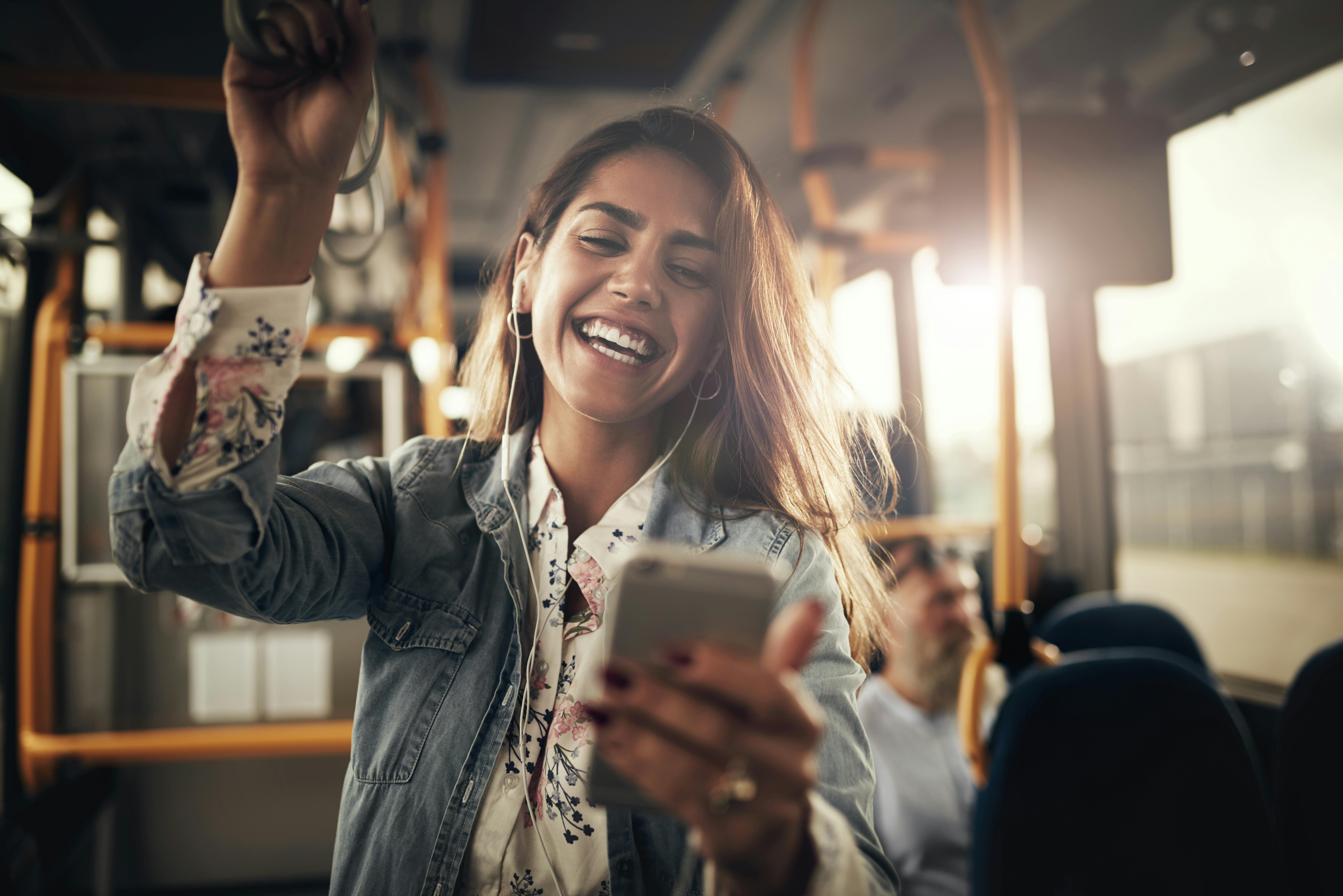 Du kan høre en sjov podcast i bussen. Kvinde der lytter til sjov podcast