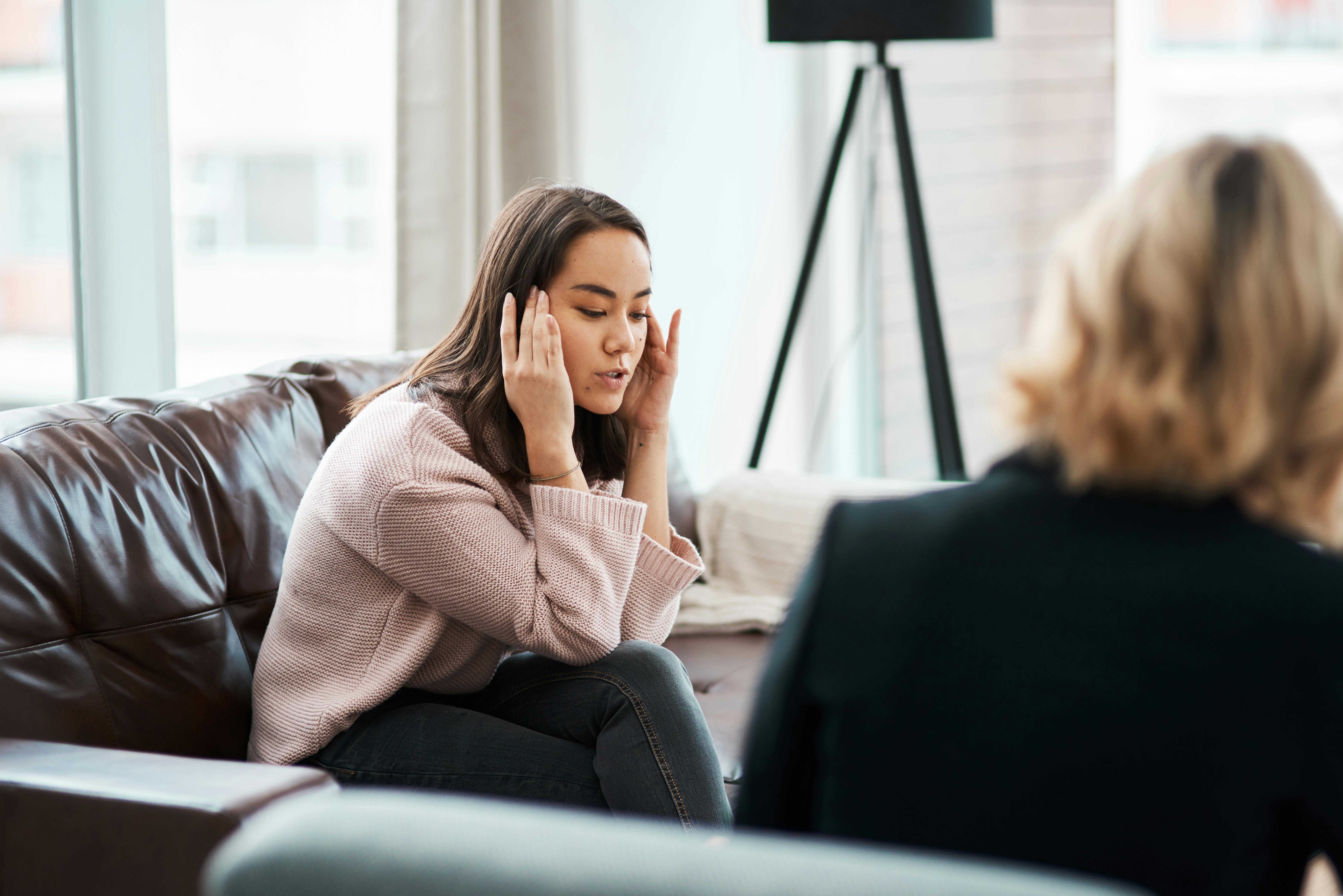 En læge eller en psykolog kan hjælpe med at finde ud af, hvornår der er tale om OCD. Kvinde sidder på en sofa og taler med en psykolog
