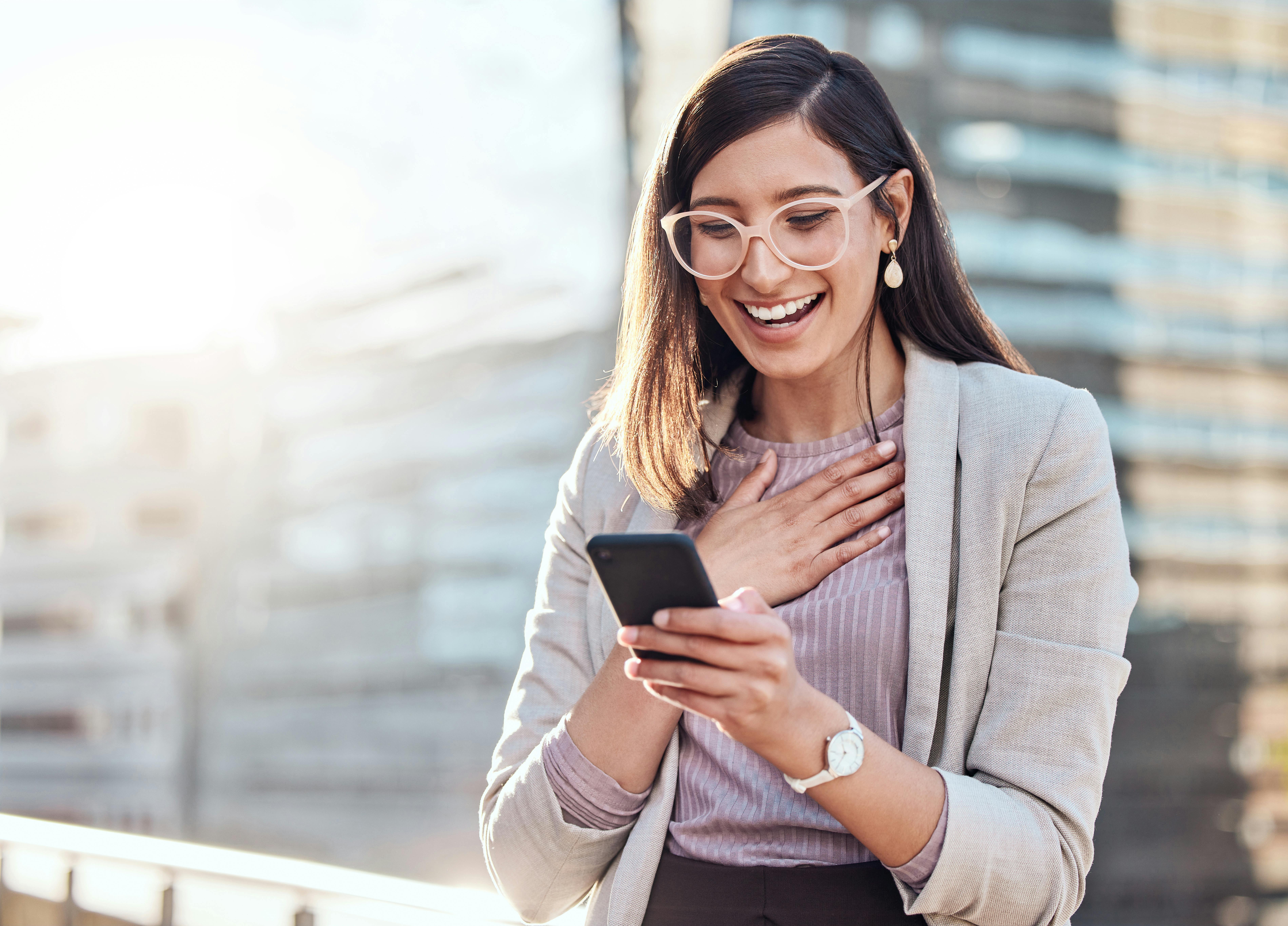 En narcissist kan bombardere dig med sms'er i starten af jeres forhold. kvinde smiler af telefon, narcissisme, narcissist