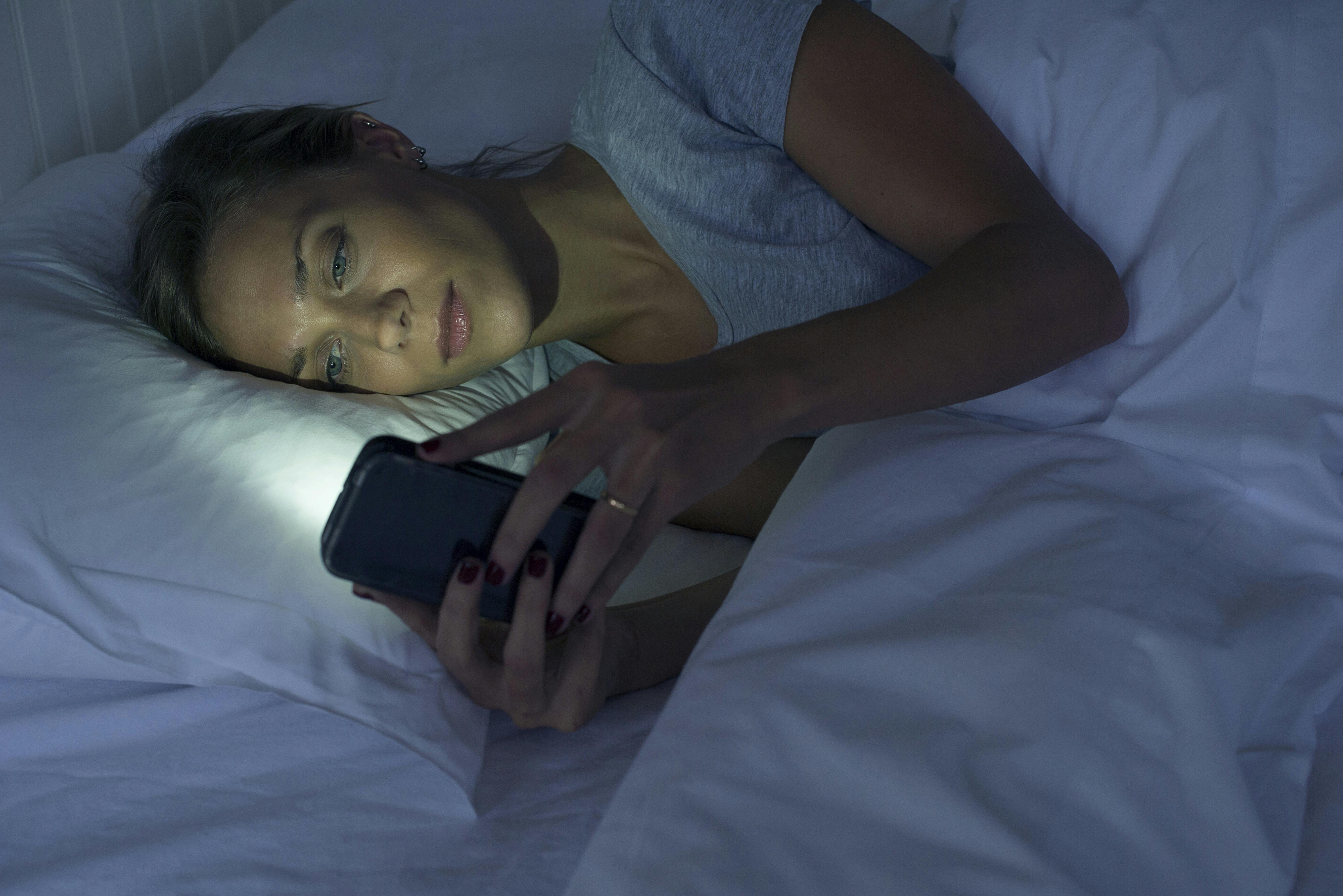 Lyset fra telefonen holder hjernen i gang. Det duer ikke lige før sengetid. Kvinde i sengen med telefon