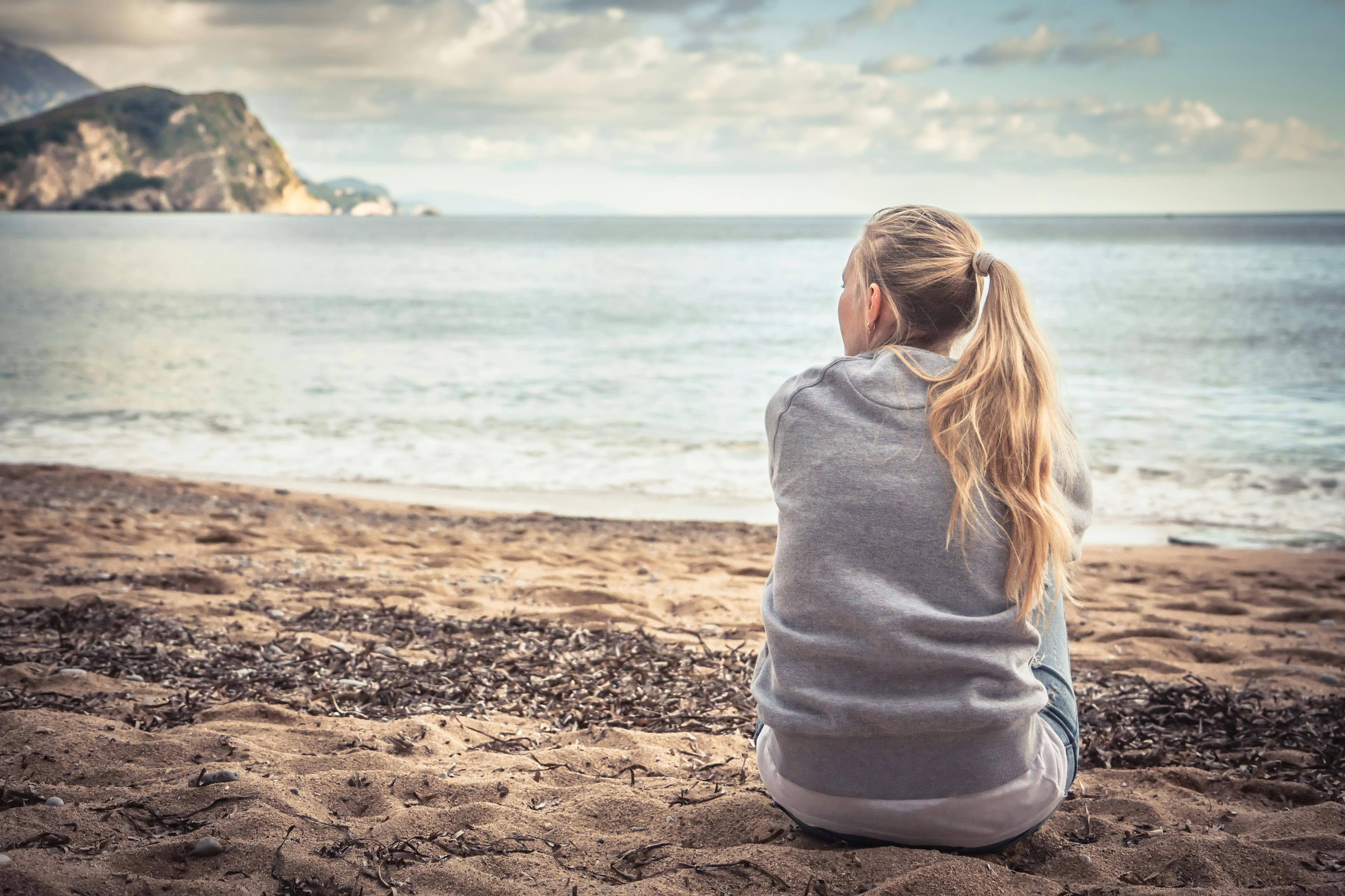 Det er muligt at lære at trives i eget selskab Kvinde sidder alene på strand og kigger på havet