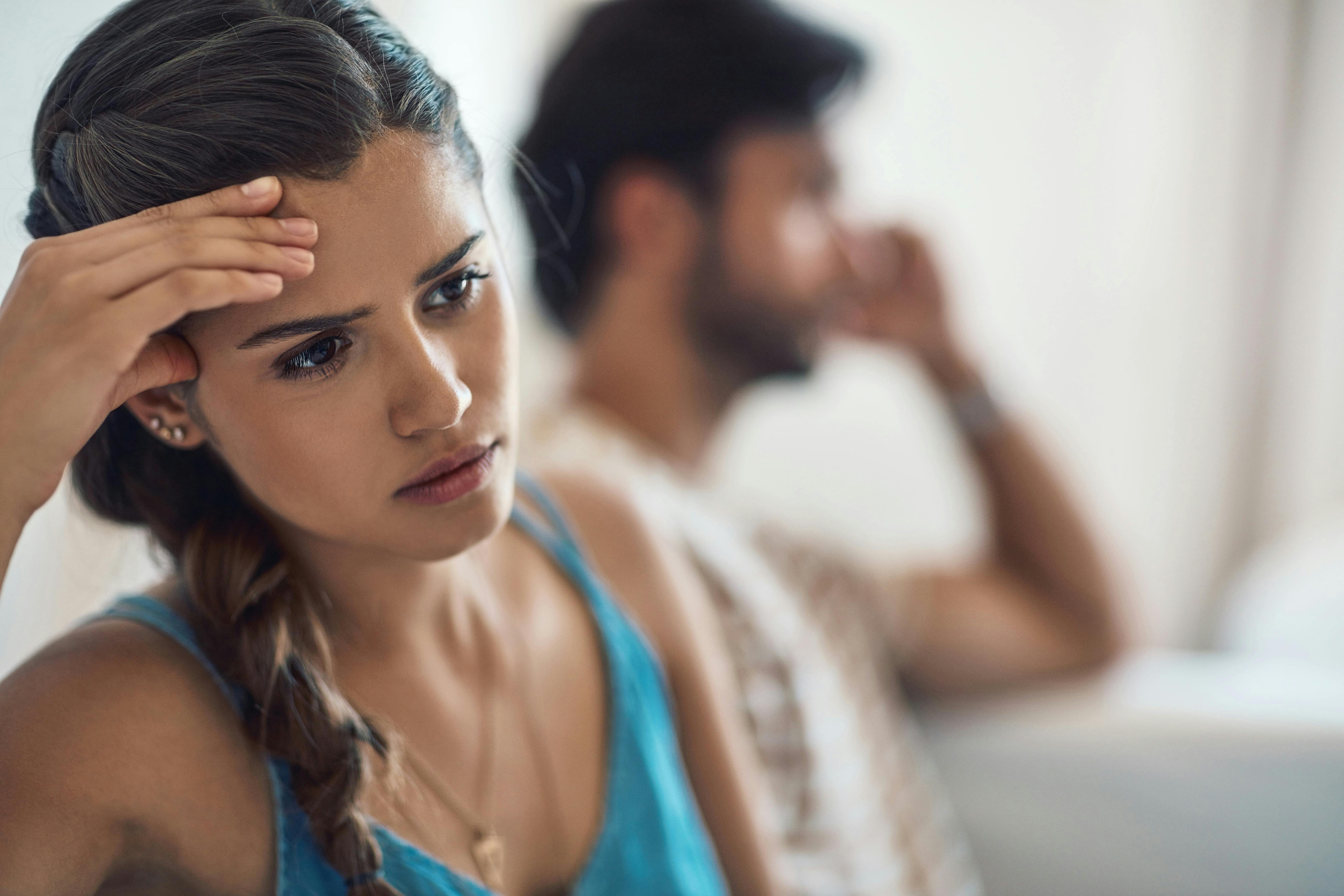 Perfektionisme kan påvirke vores relationer til dem, vi har omkring os. Kvinde og mand sidder i sofa og ser bekymrede ud