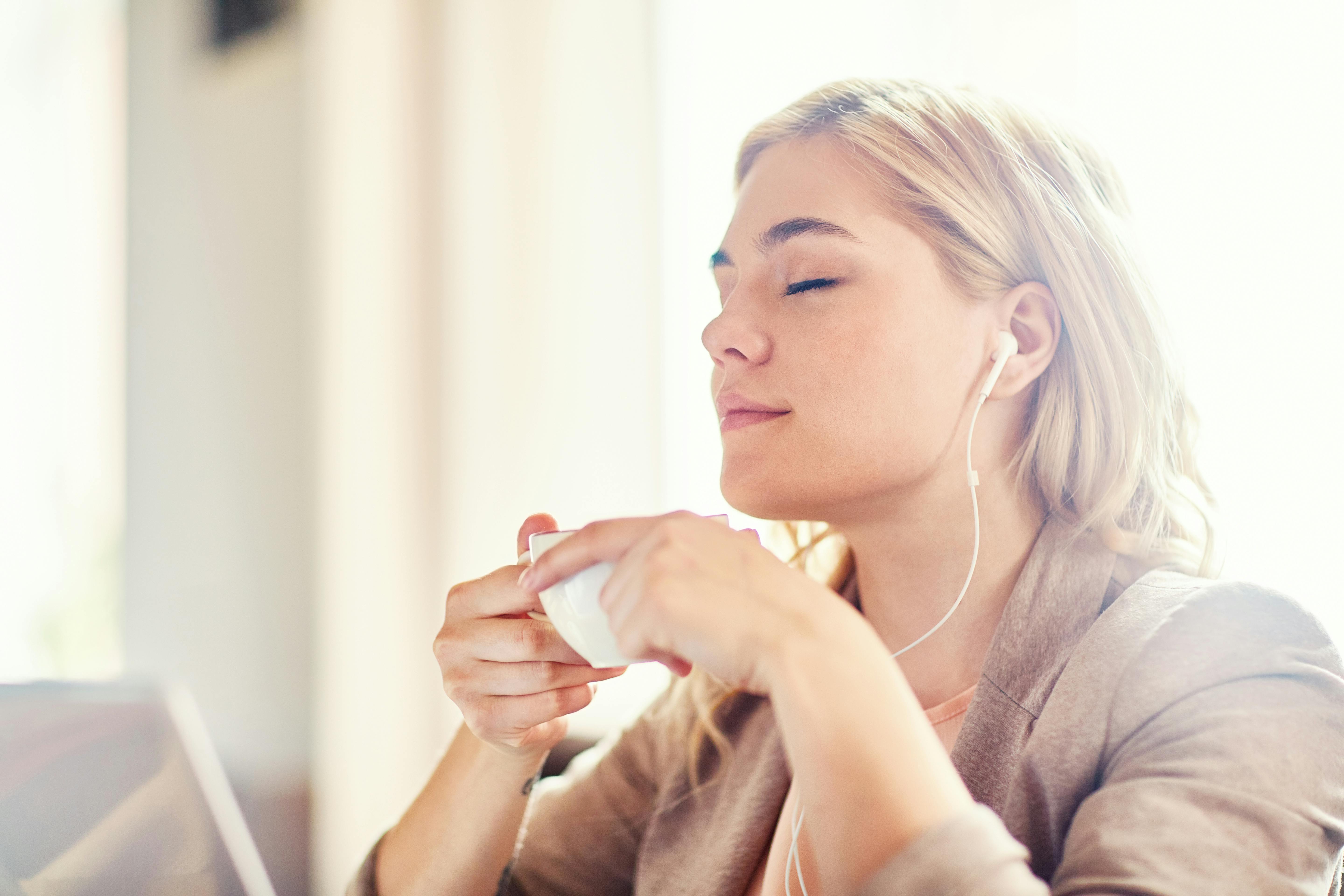 Skal du på date på trods af angsten? Så prøv at slappe af med noget behagligt musik. En kvinde slapper af med en kop kaffe og musik i ørerne