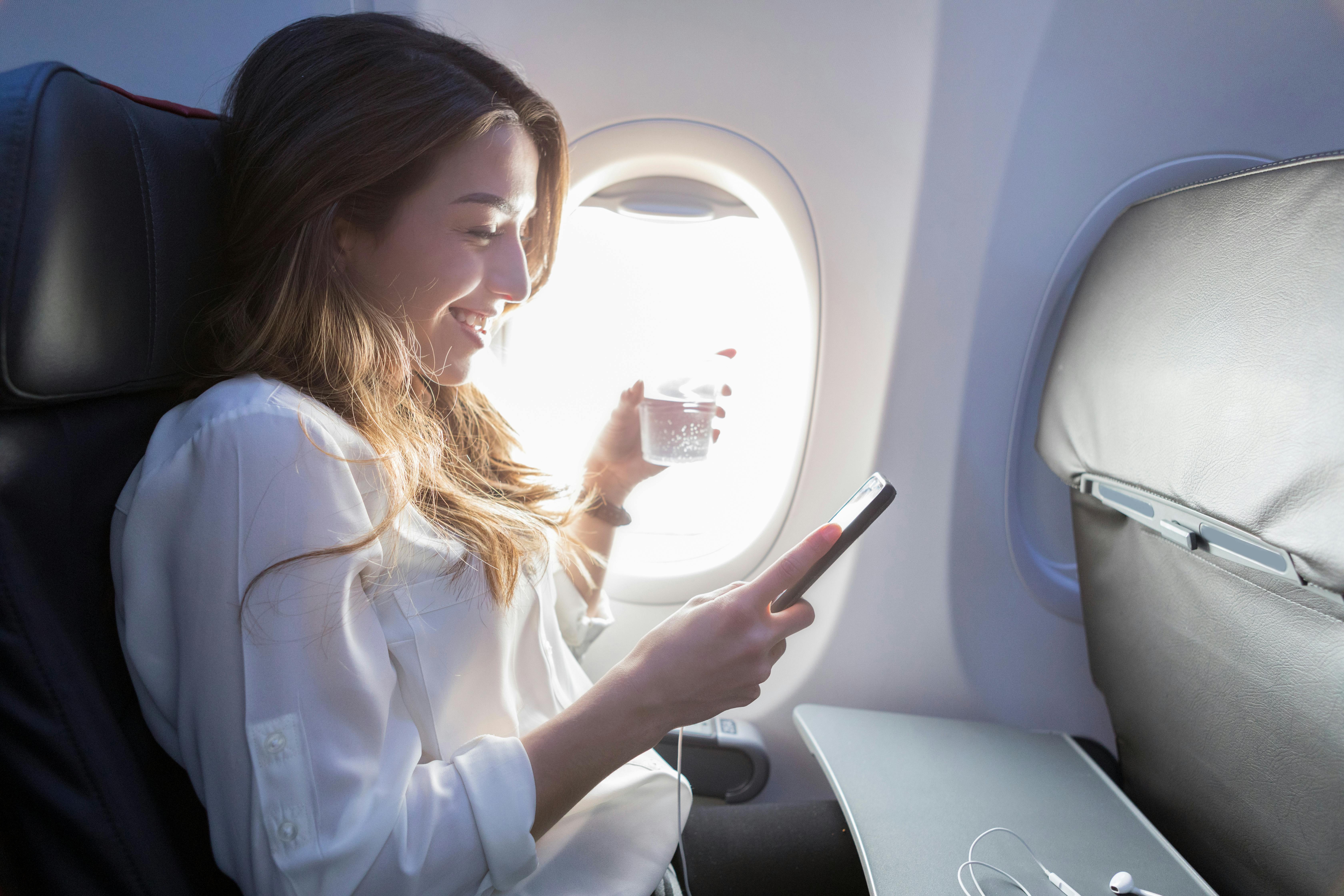 Husk at drikke rigeligt med væske på flyet, så du ikke får slem jetlag. Kvinde drikker væske på fly