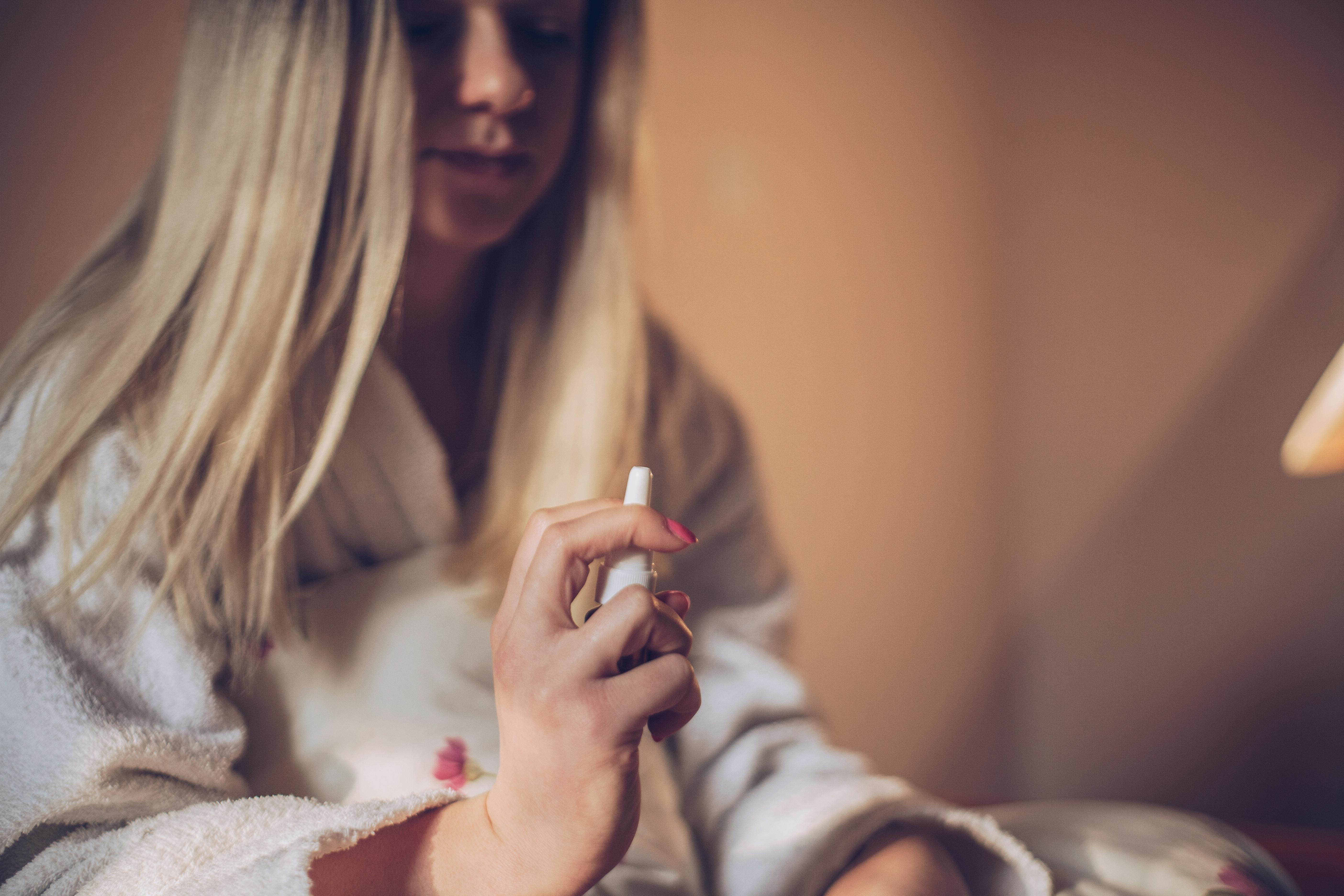 Lav din egen hjemmelavede næsespray mod stoppet næse. Kvinde sidder med sin næsespray mod stoppet næse.