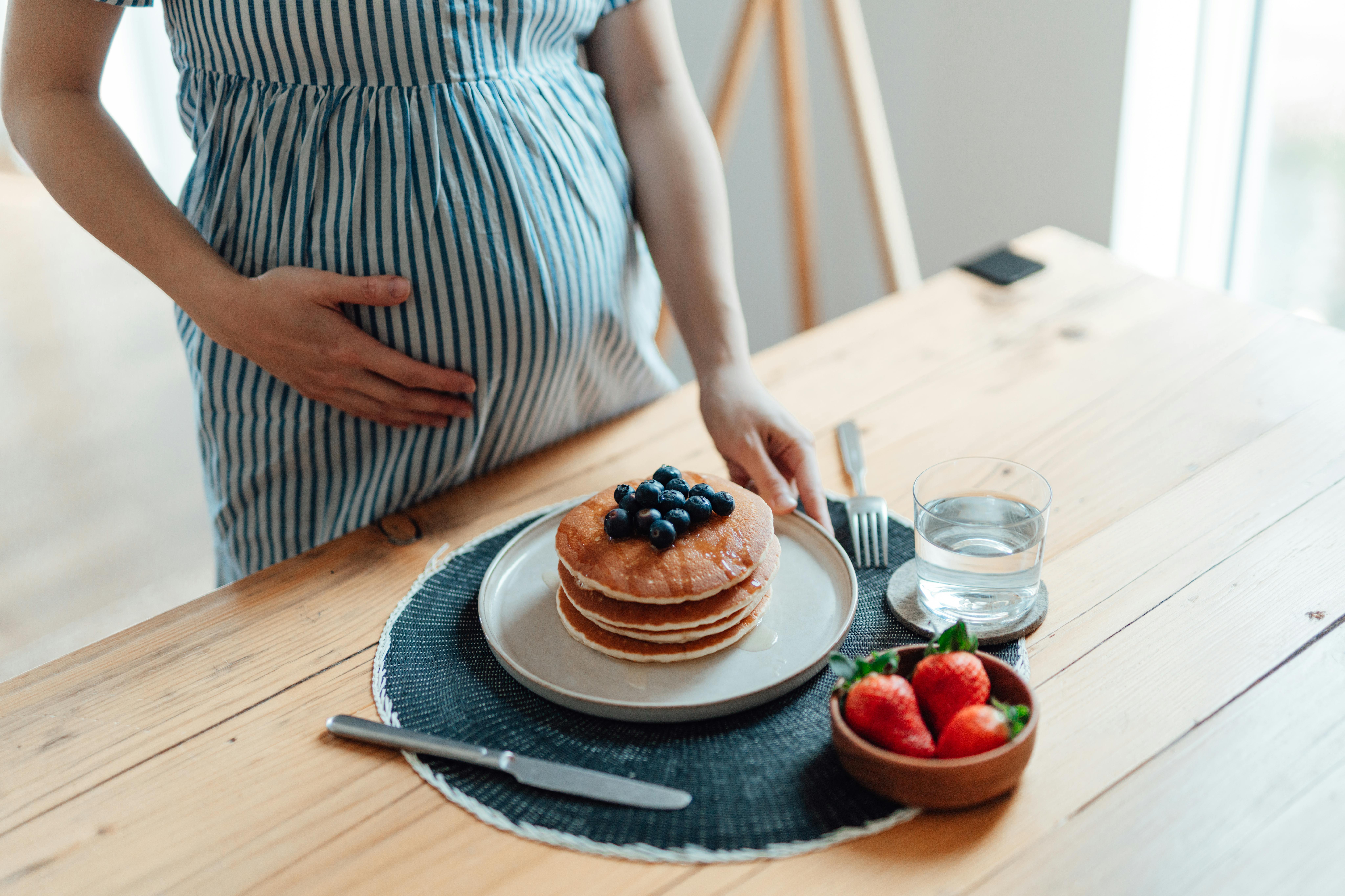 Fostret begynder at kunne smage ting i uge 21 af graviditeten. Kvinde gravid i uge 20 står foran pandekager