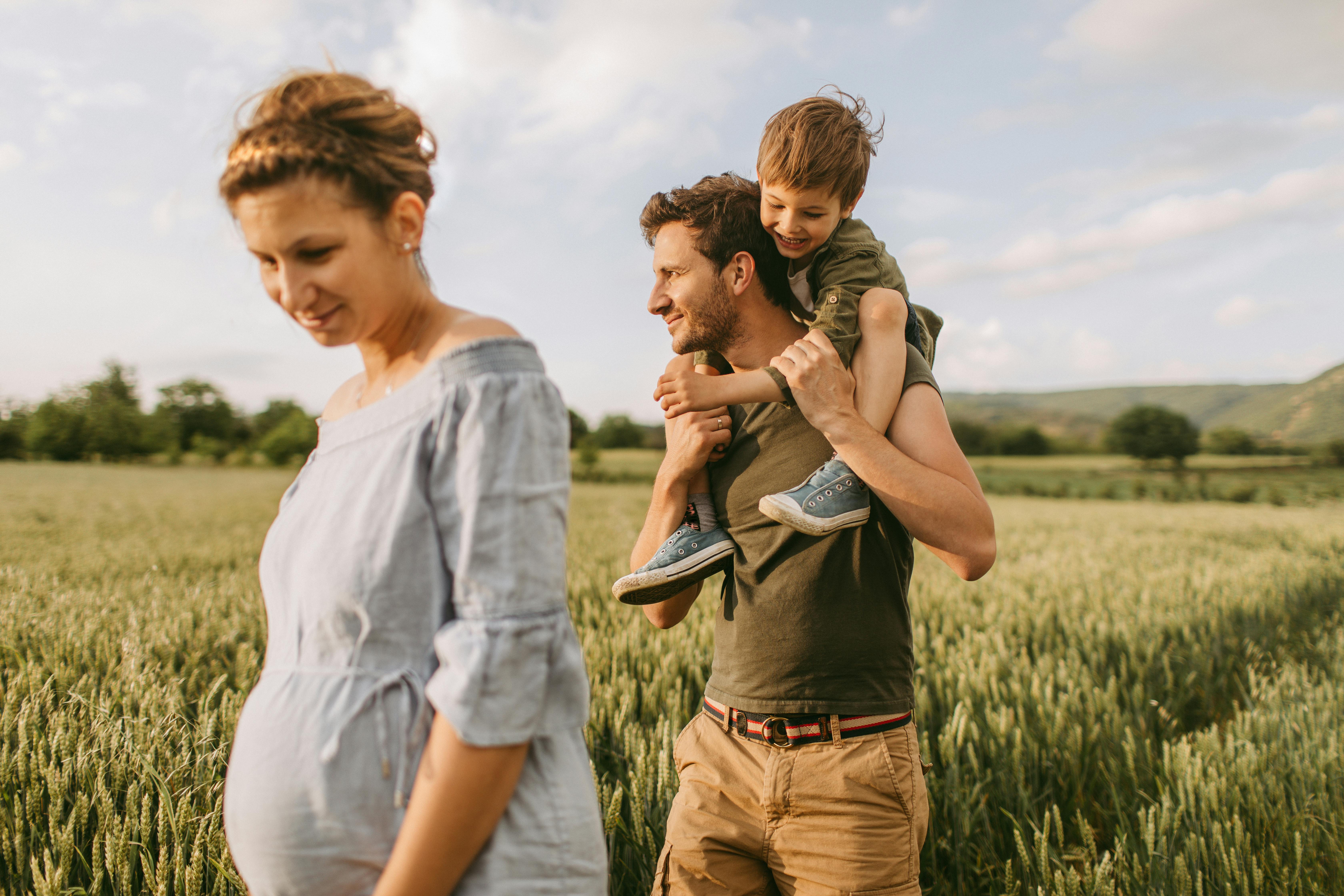 Når du er gravid i uge 25, vil andre omkring dig kunne mærke sparkene i maven. Kvinde, som er gravid i uge 25, er sammen med mand og søn