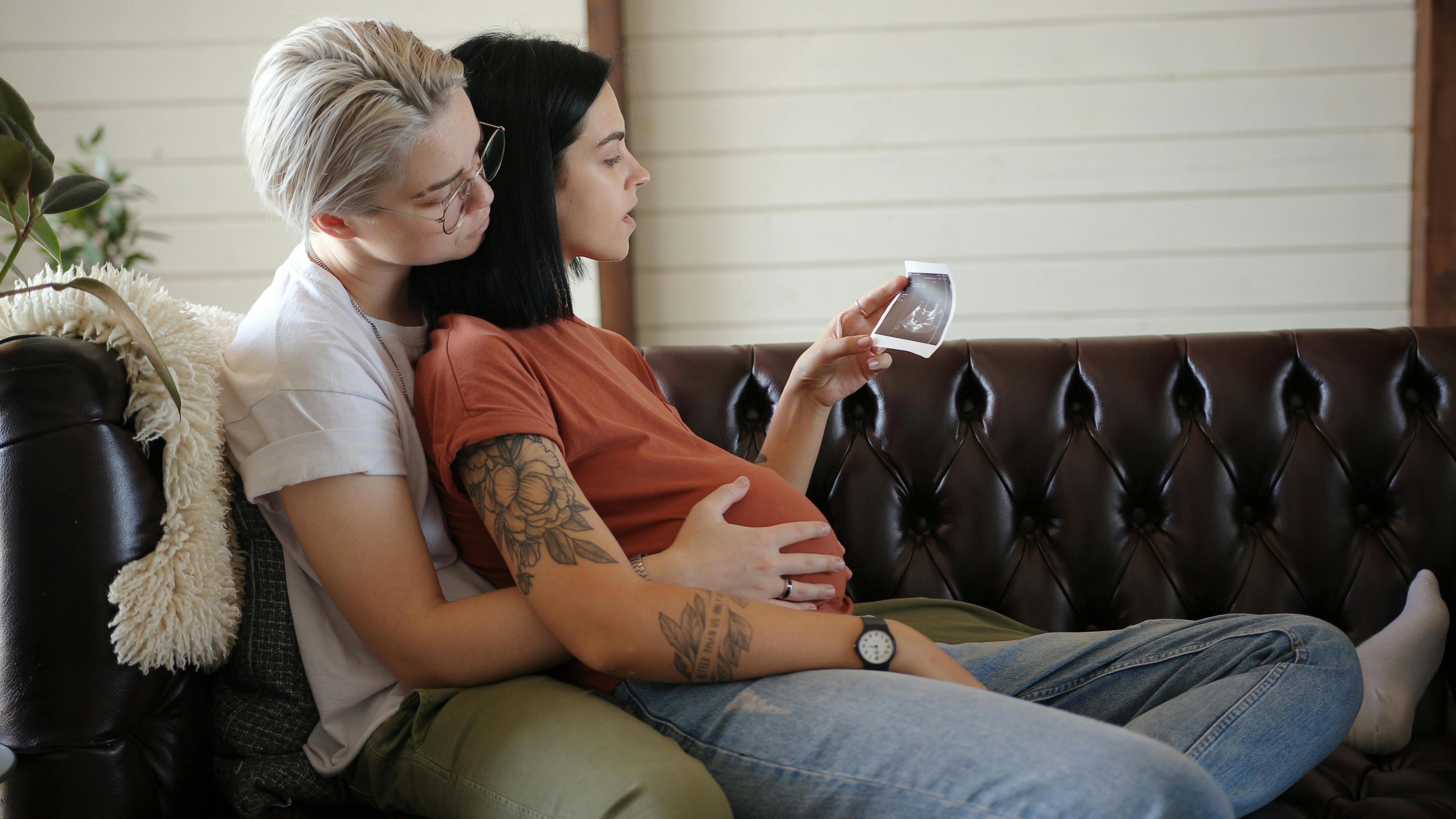 Din krop er tæt på at være klar til fødslen, når du er gravid i uge 35. Kvinde, der er gravid i uge 35, sidder på sofa med sin partner