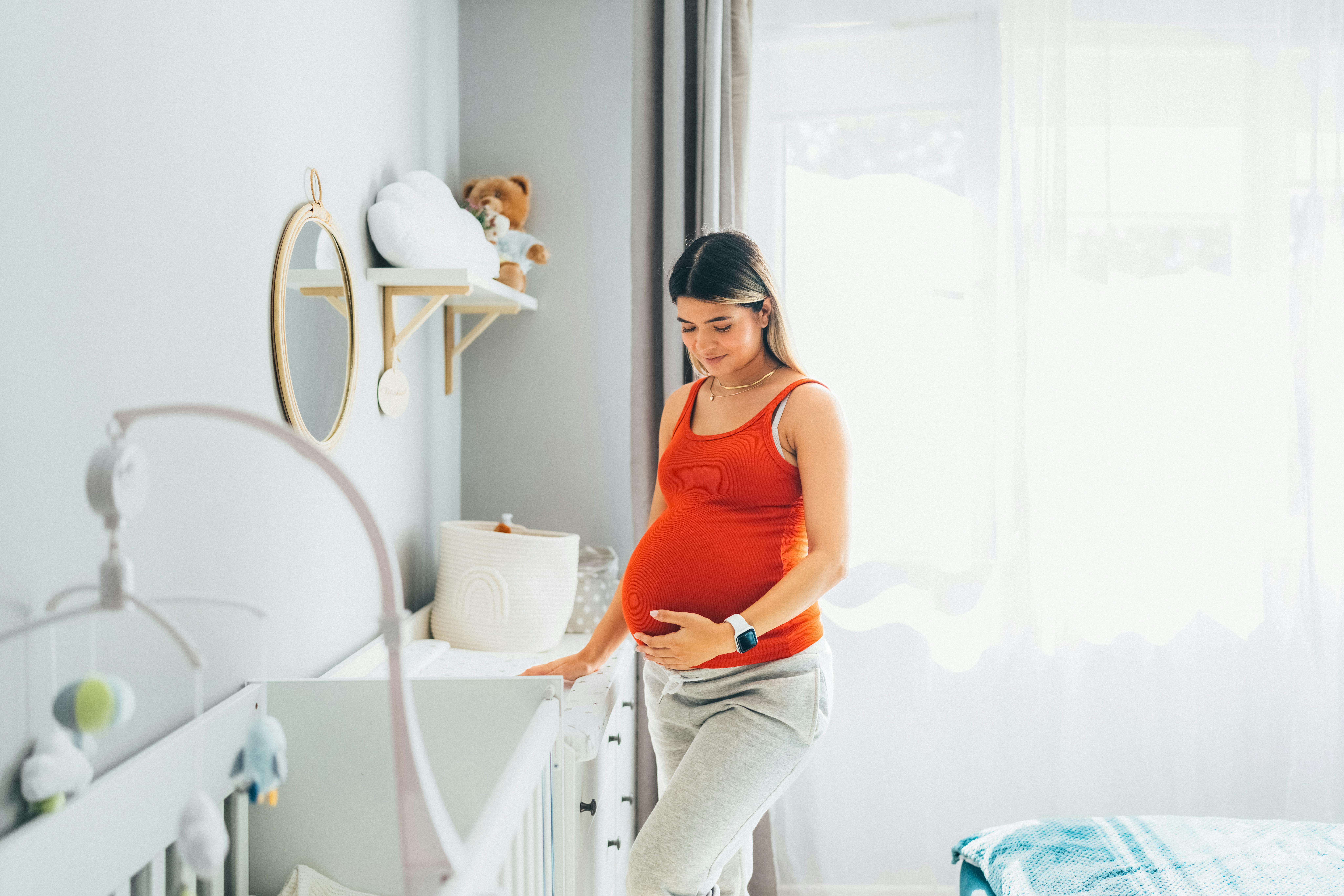 Du er måske ved at have de praktiske ting på plads, når du er gravid i uge 39. Kvinde, som er gravid i uge 39, står inde på børneværelse