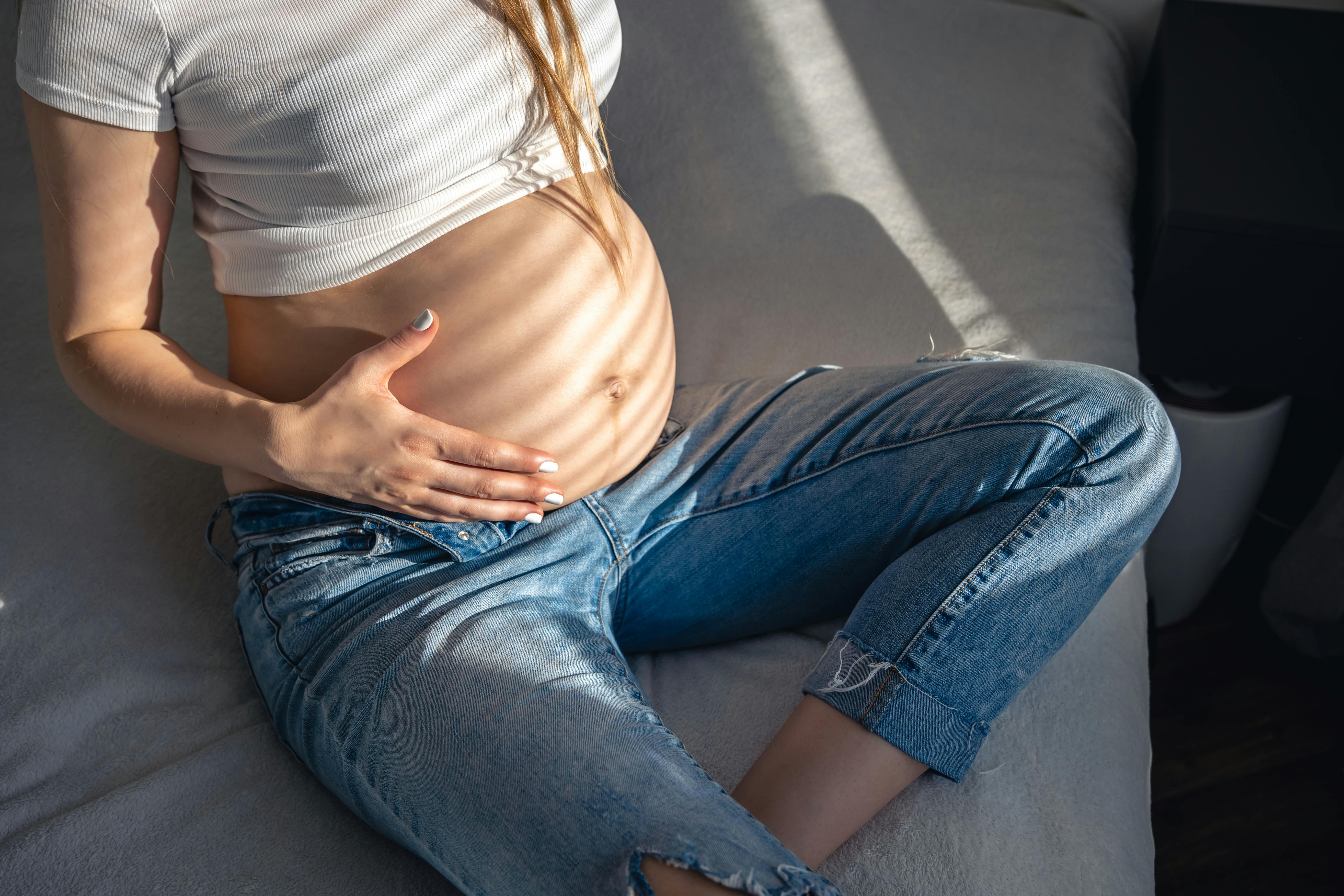 Maven bliver større og større her i uge 23 af graviditeten. Kvinde, der er gravid i uge 23, rører sin mave