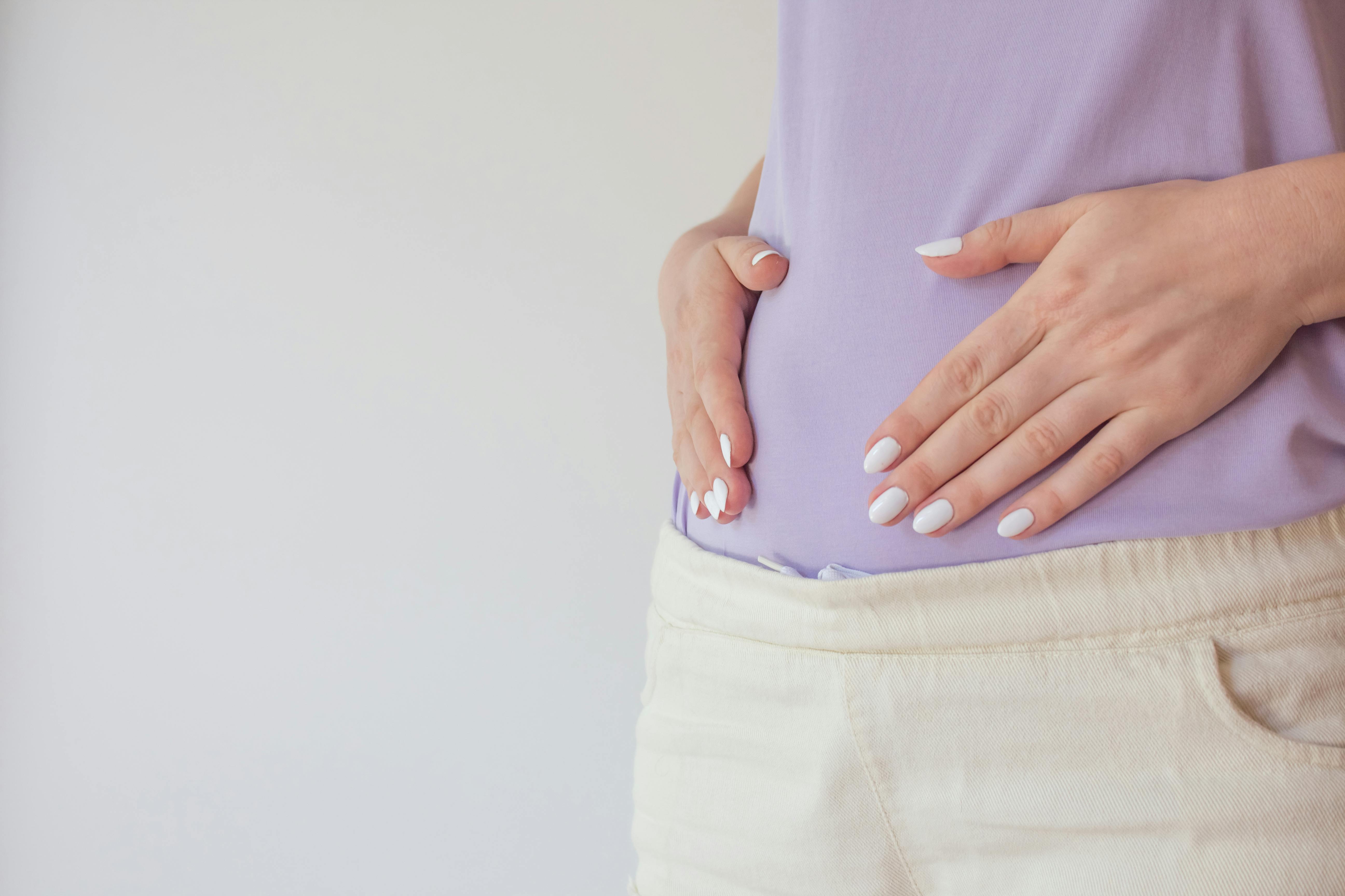 Du kan måske mærke aktivitet i maven som gravid i uge 15. Kvinde, som er gravid i uge 15, rører sin mave