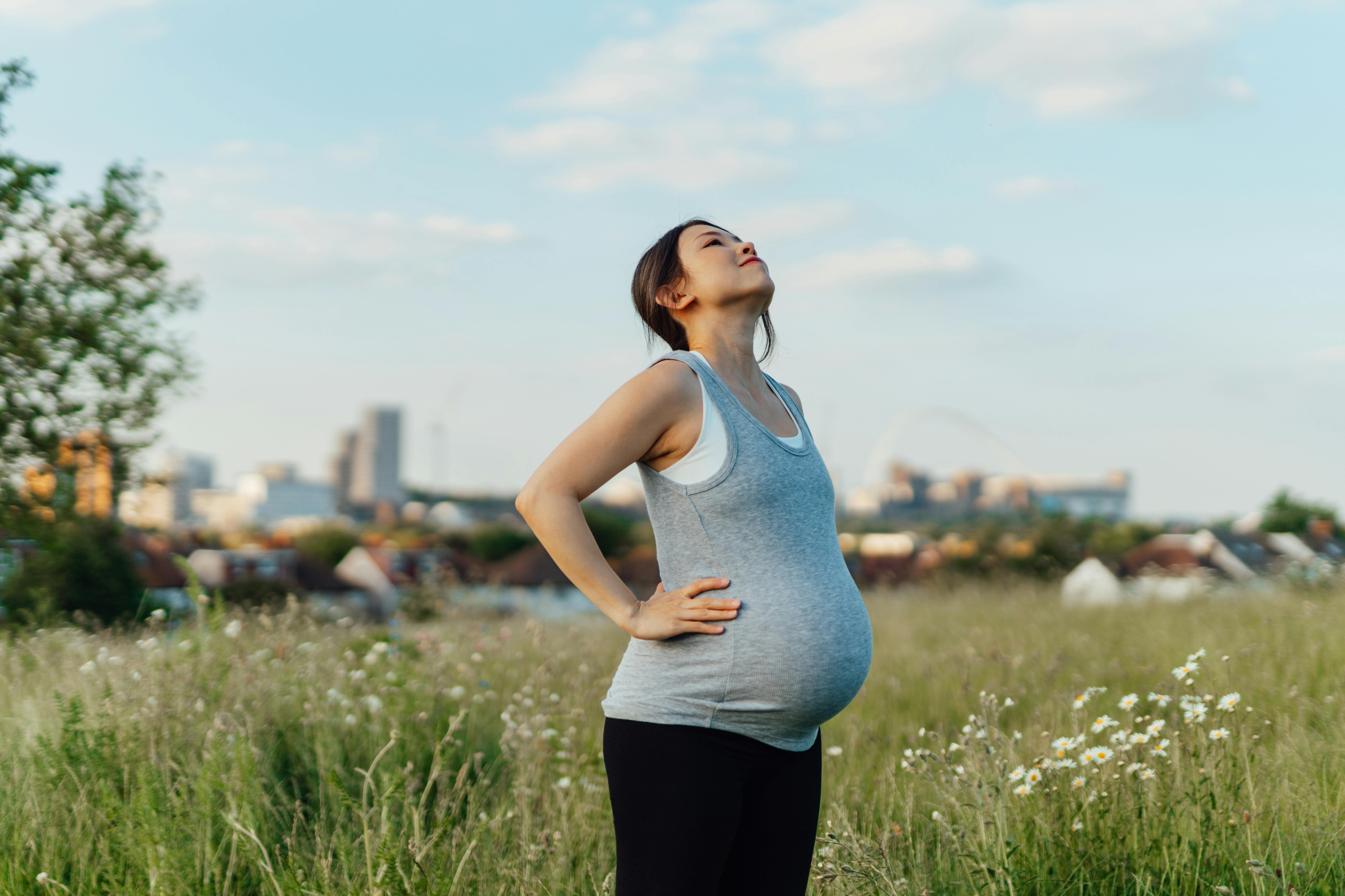 Maven er blevet ret stor her i uge 25 af graviditeten. Kvinde, som er gravid i uge 25, er ude i naturen