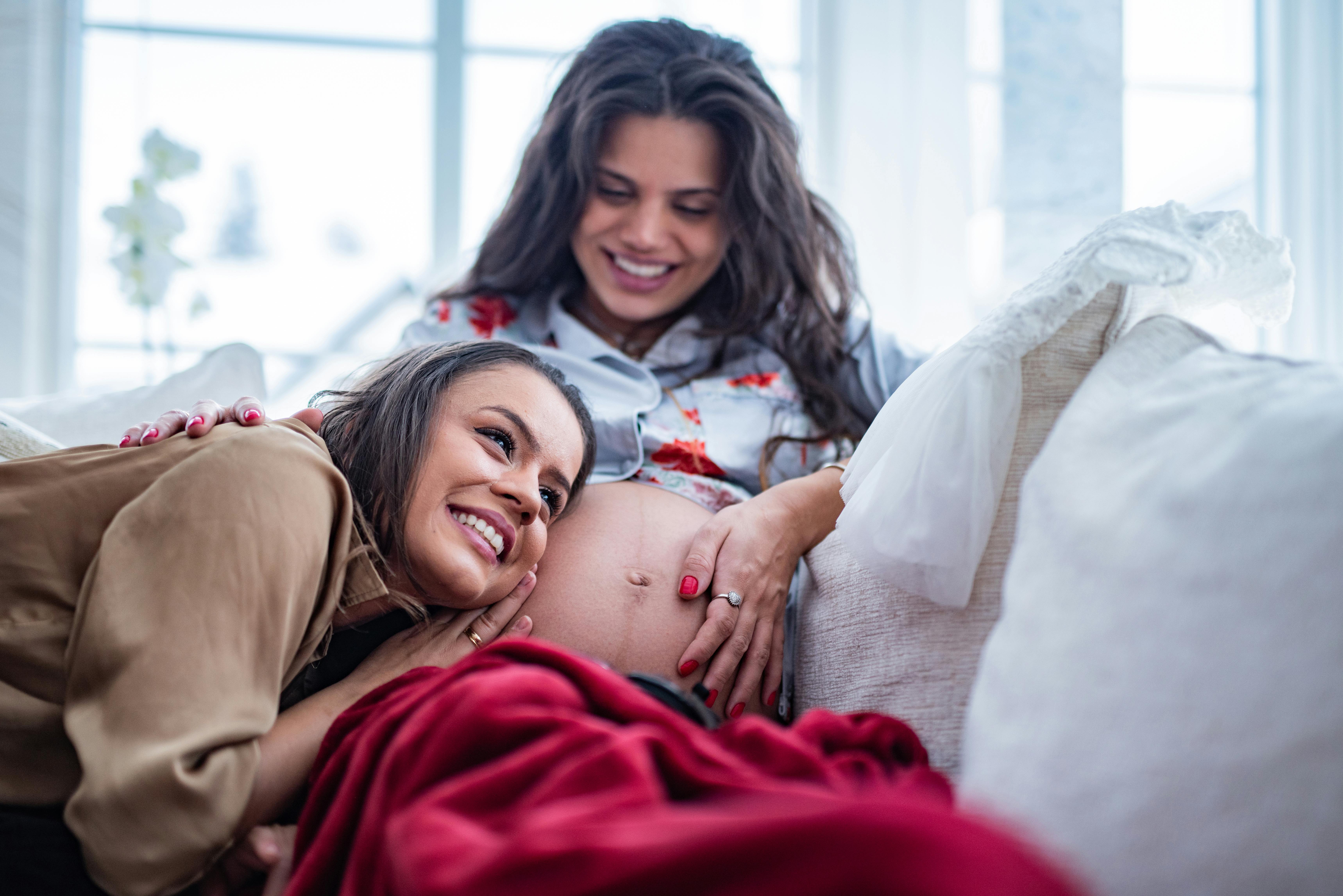 Når du er gravid i uge 36, har fostret ikke længere så meget plads som tidligere. Kvinde, der er gravid i sofaen, sidder med veninde eller partner i sofaen