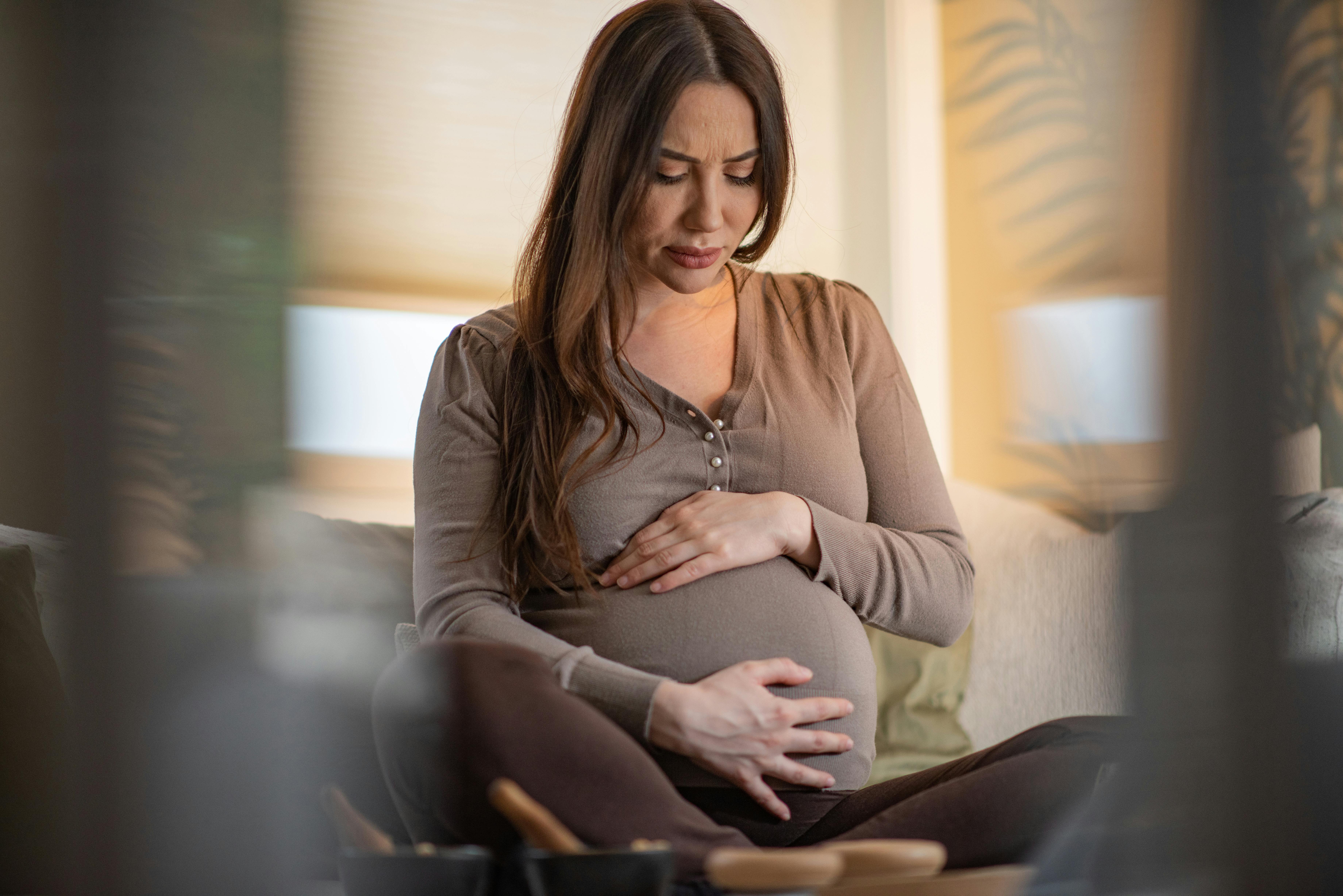 Vær forsigtig, så du ikke overbelaster dig selv her i uge 35 af din graviditet. Kvinde, som er gravid i uge 36, sidder i sin sofa