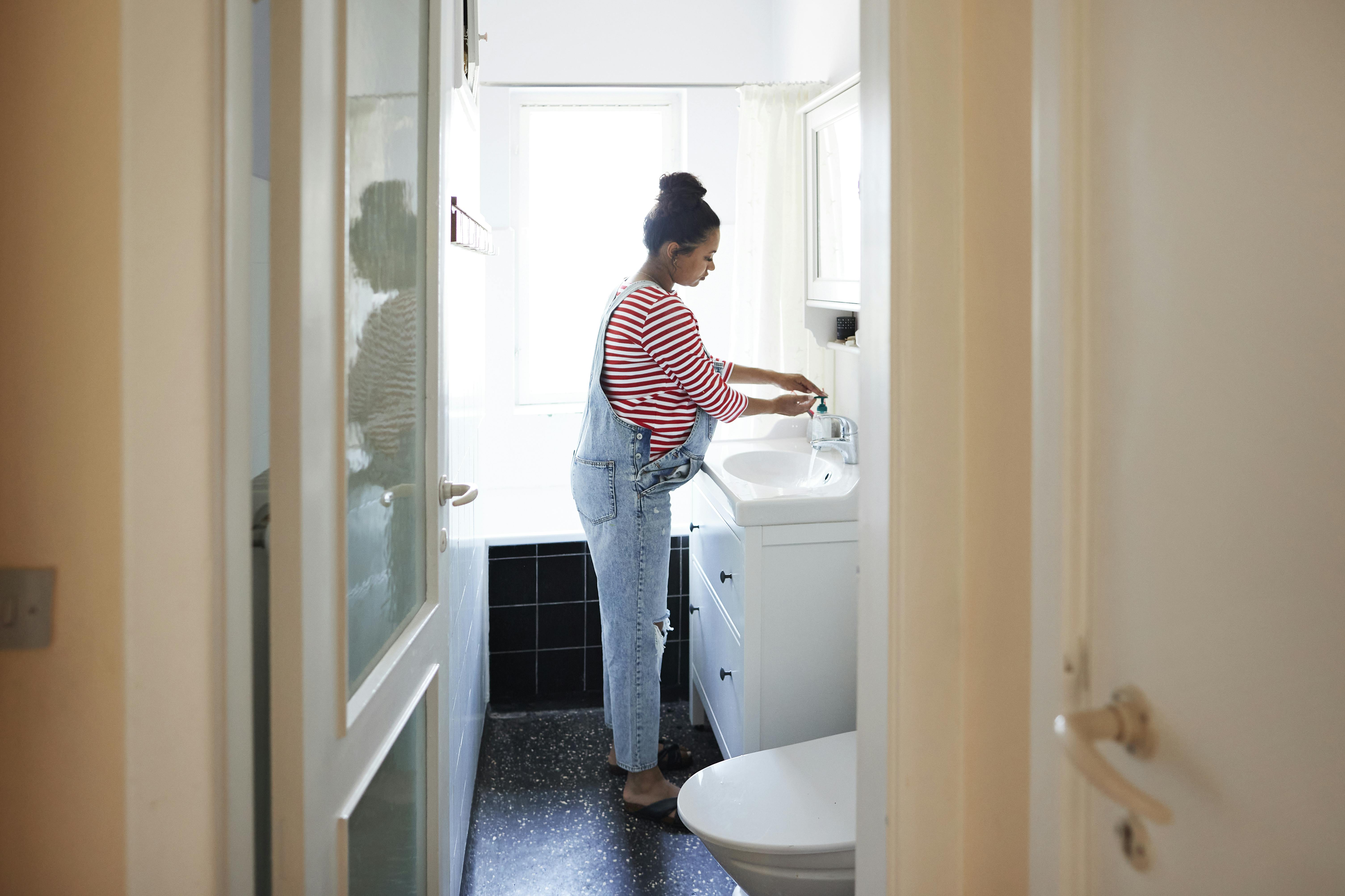 Din mave kan føles meget tung og hård her i uge 39 af din graviditet. Kvinde, der er gravid i uge 39, står på badeværelset