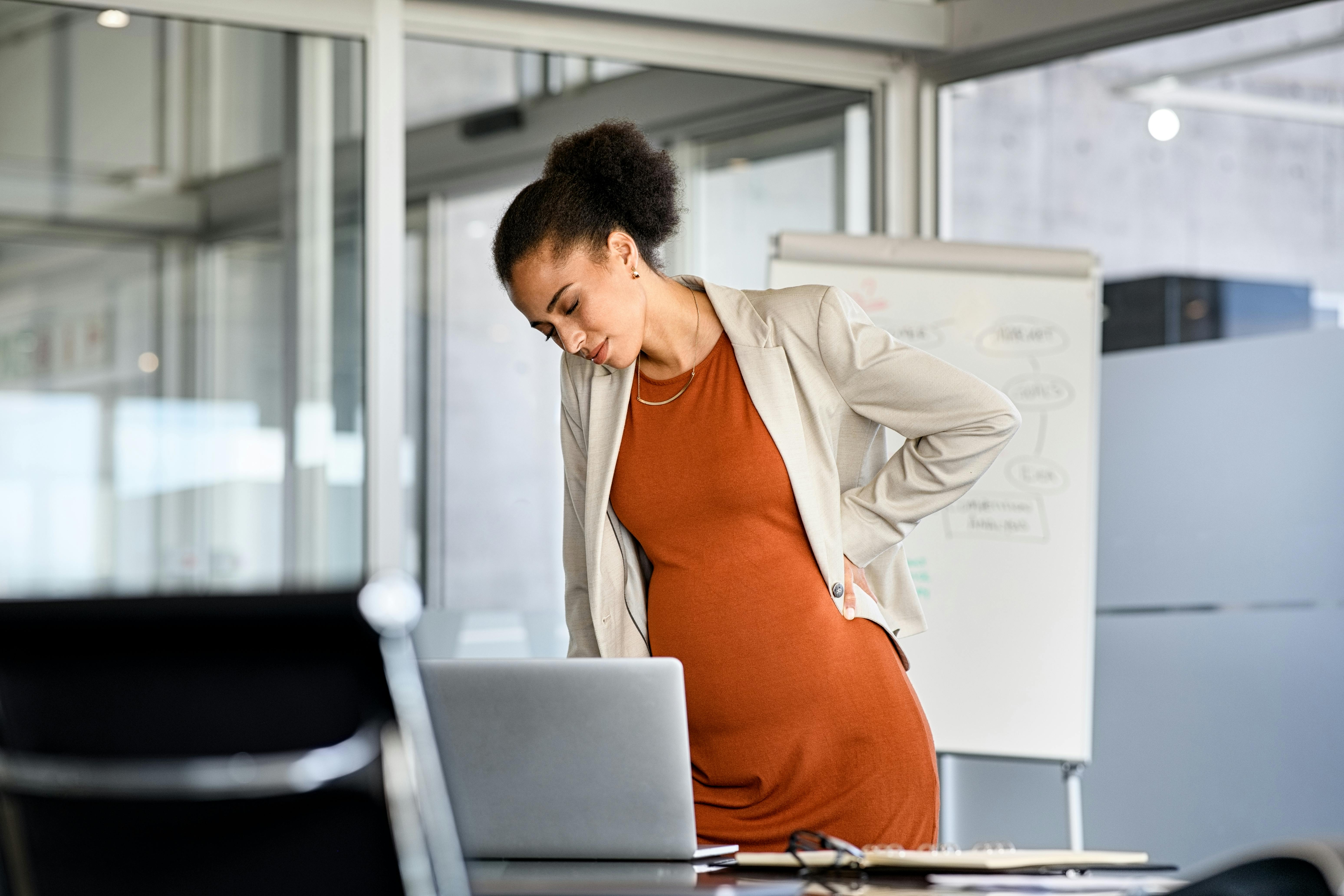 Det kan føles tungt at bevæge dig, når du er gravid i uge 28. Kvinde, som er gravid i uge 28, er på arbejde