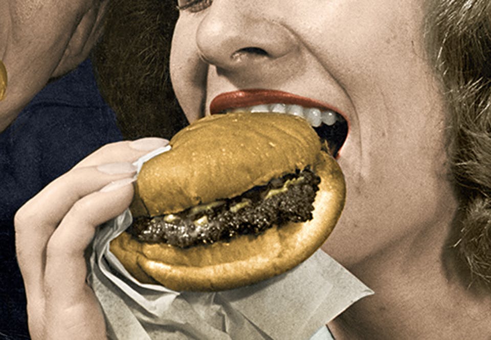 Kvinna som äter en hamburgare.
