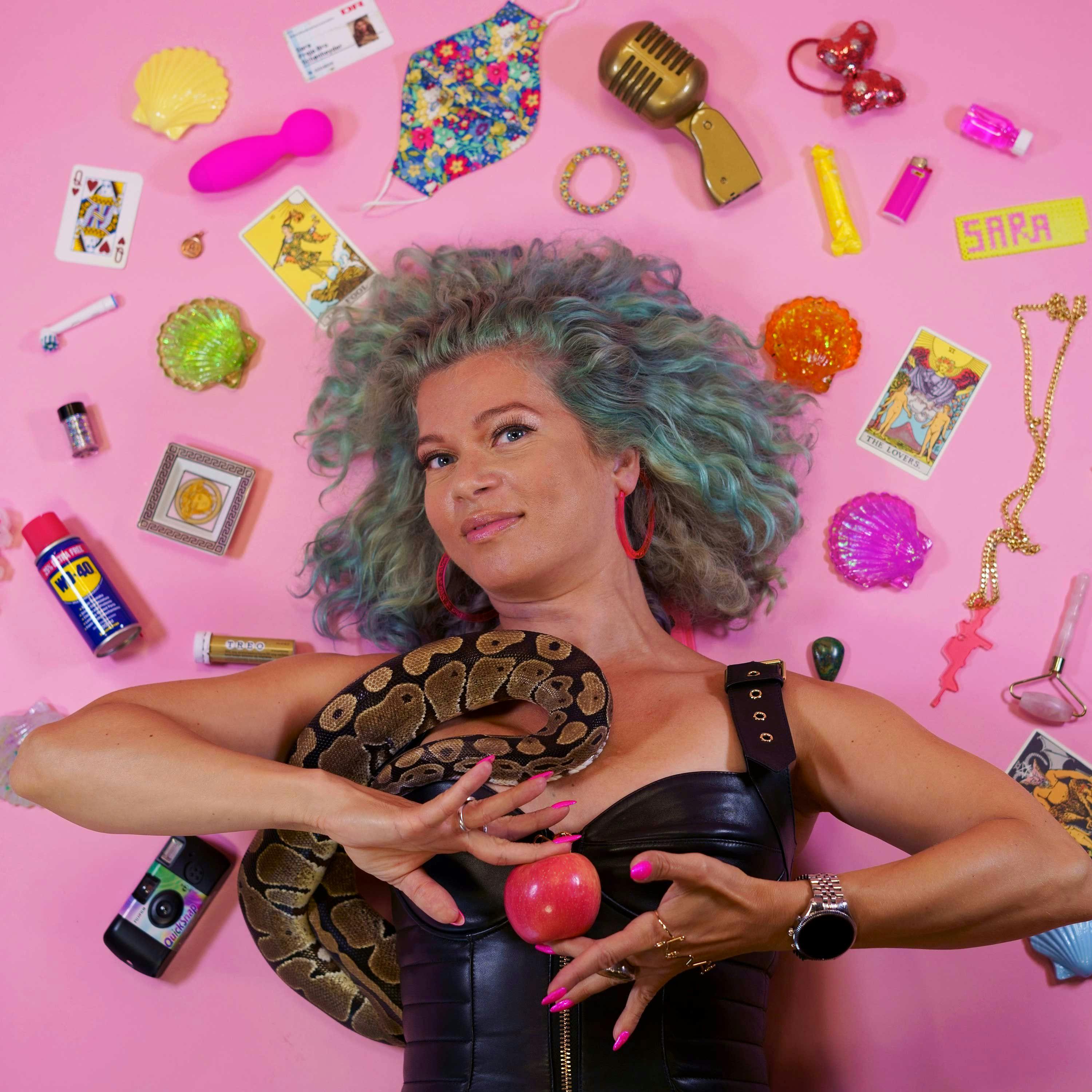 Sara Bro er vært på podcasten Hjerteflimmer for voksne Kvinde på pink baggrund