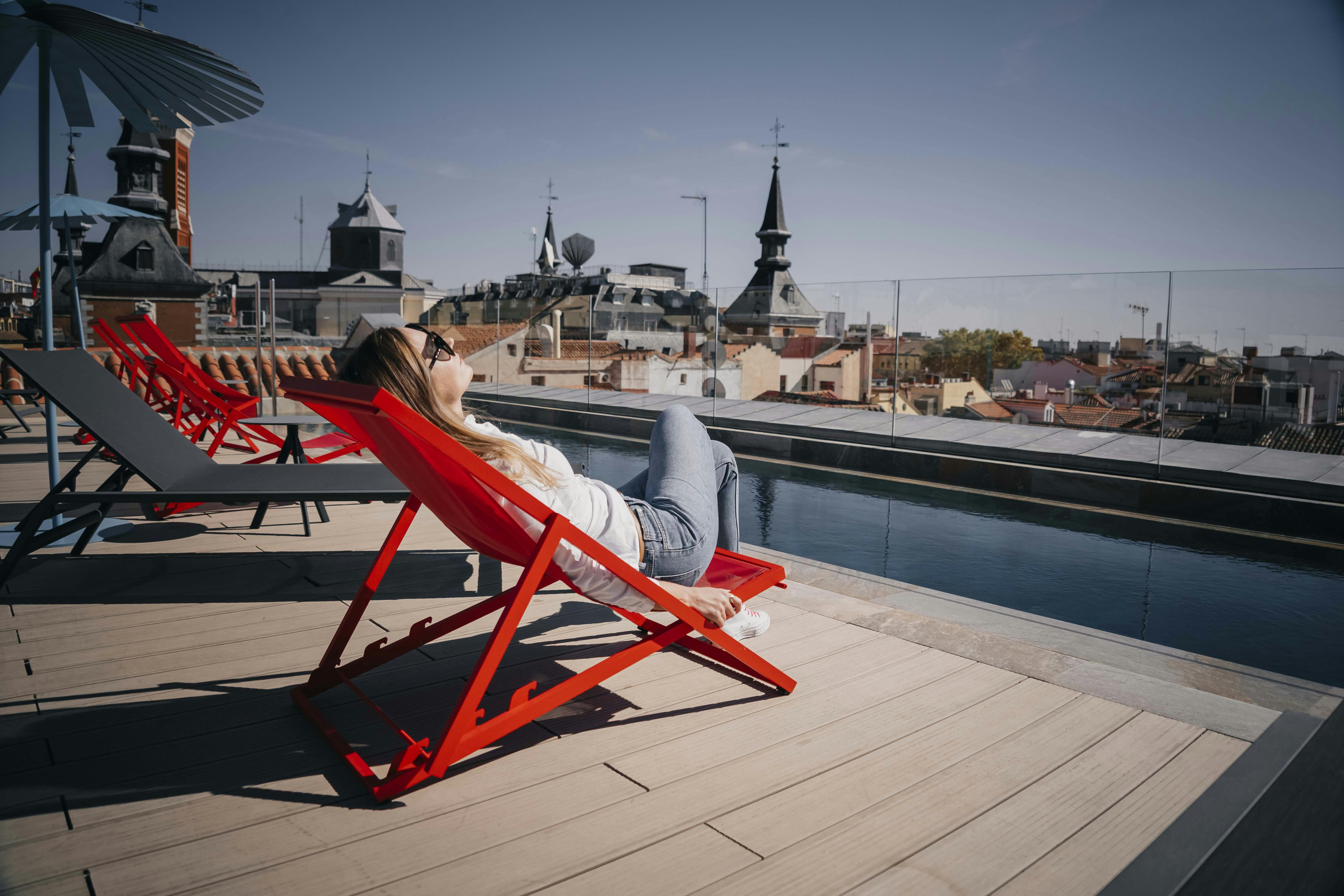 Fra maj til oktober er Madrids gennemsnitstemperatur over 20 grader! Kvinde, der slapper af i liggestol på tagterrasse.