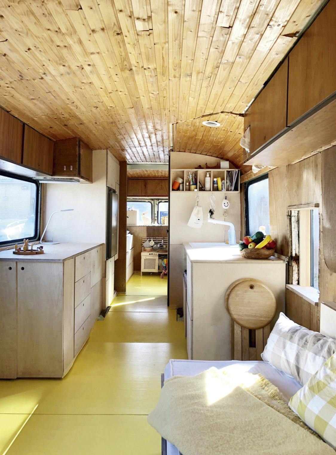 De woonkeuken van berkenfineer ontleent de bovenkastjes aan vliegtuigdesign omgebouwde leger bus camper mobilehome