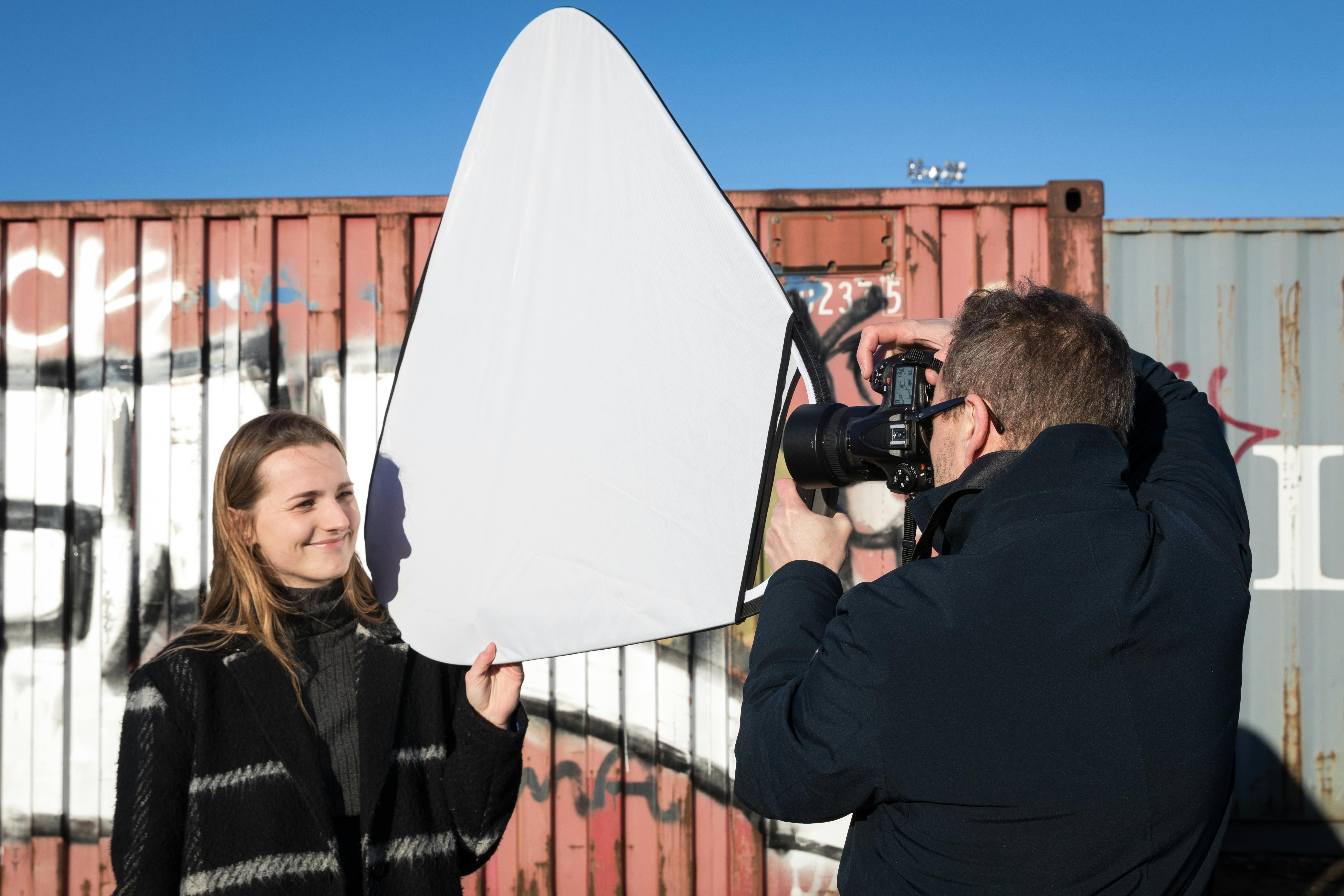 Porträtt i dagsljus Fotograf tar porträttbild med reflektor