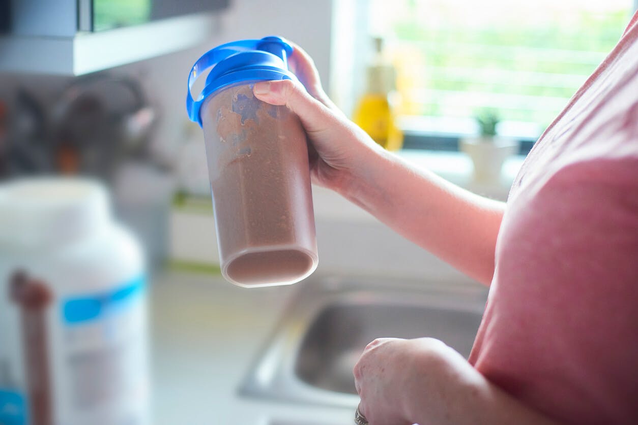 Proteinshake Kvinna håller en proteinshake i handen.