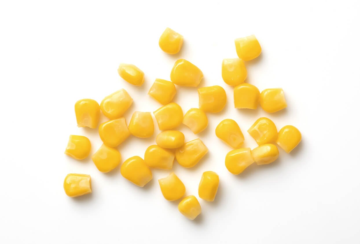Mais smaker ikke bare godt - Gule maiskorn på hvit bakgrunn