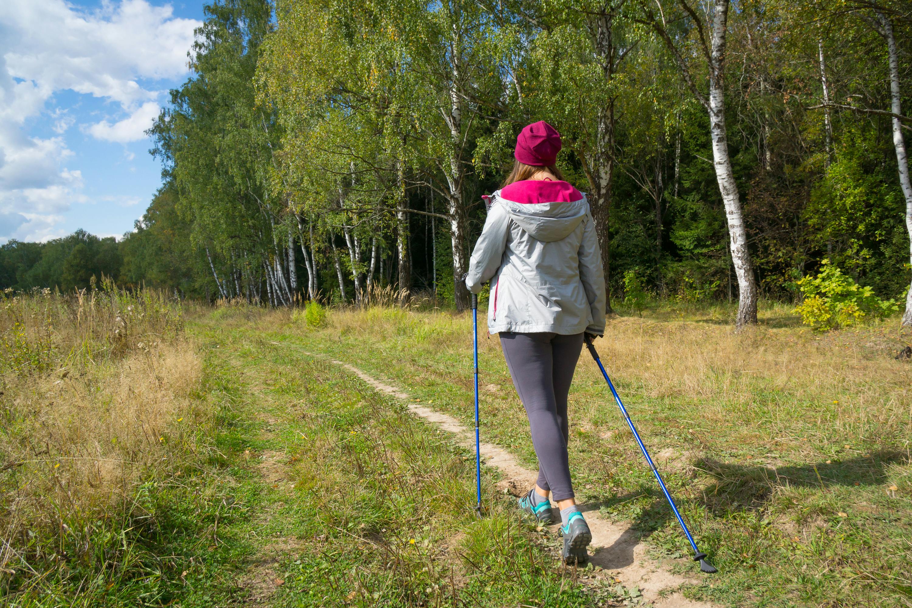 Kvinde går stavgang ude i grøn natur