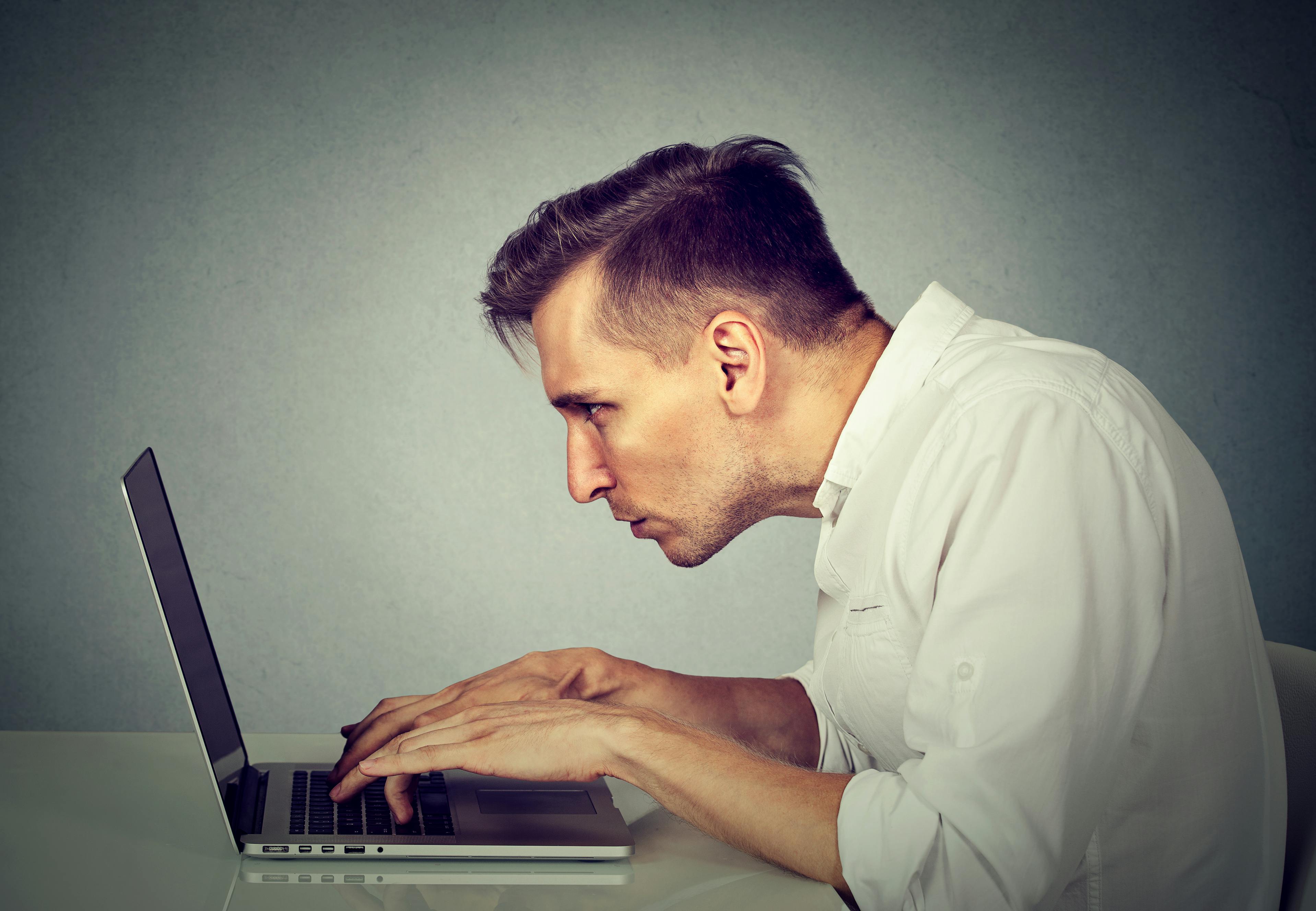 Mand der sidder krumbøjet foran en computer.