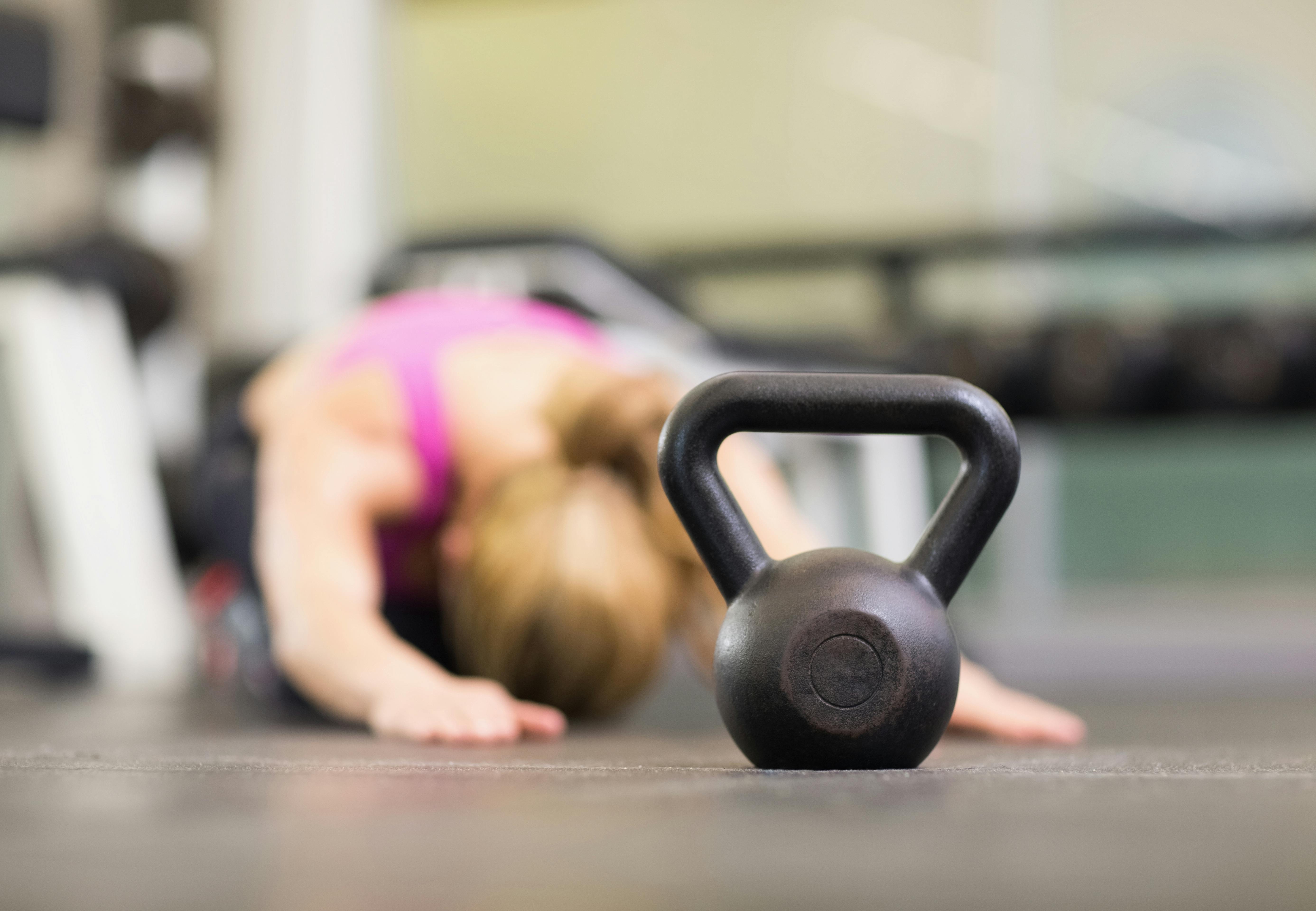 Kvinde strækker ud, kettlebell i forgrunden