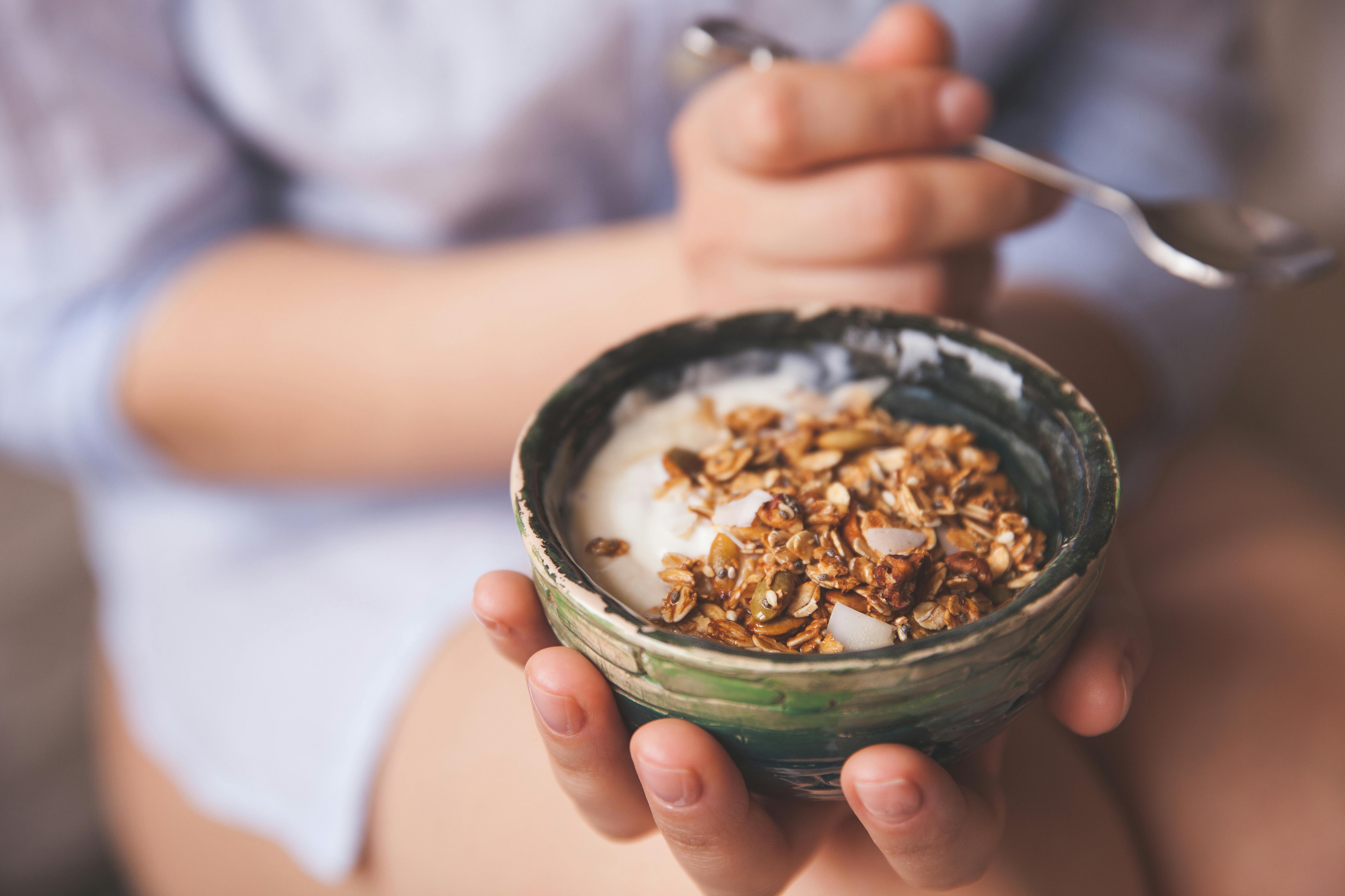 Pro- og præbiotika Kvinde sidder med en skål med yoghurt og mysli