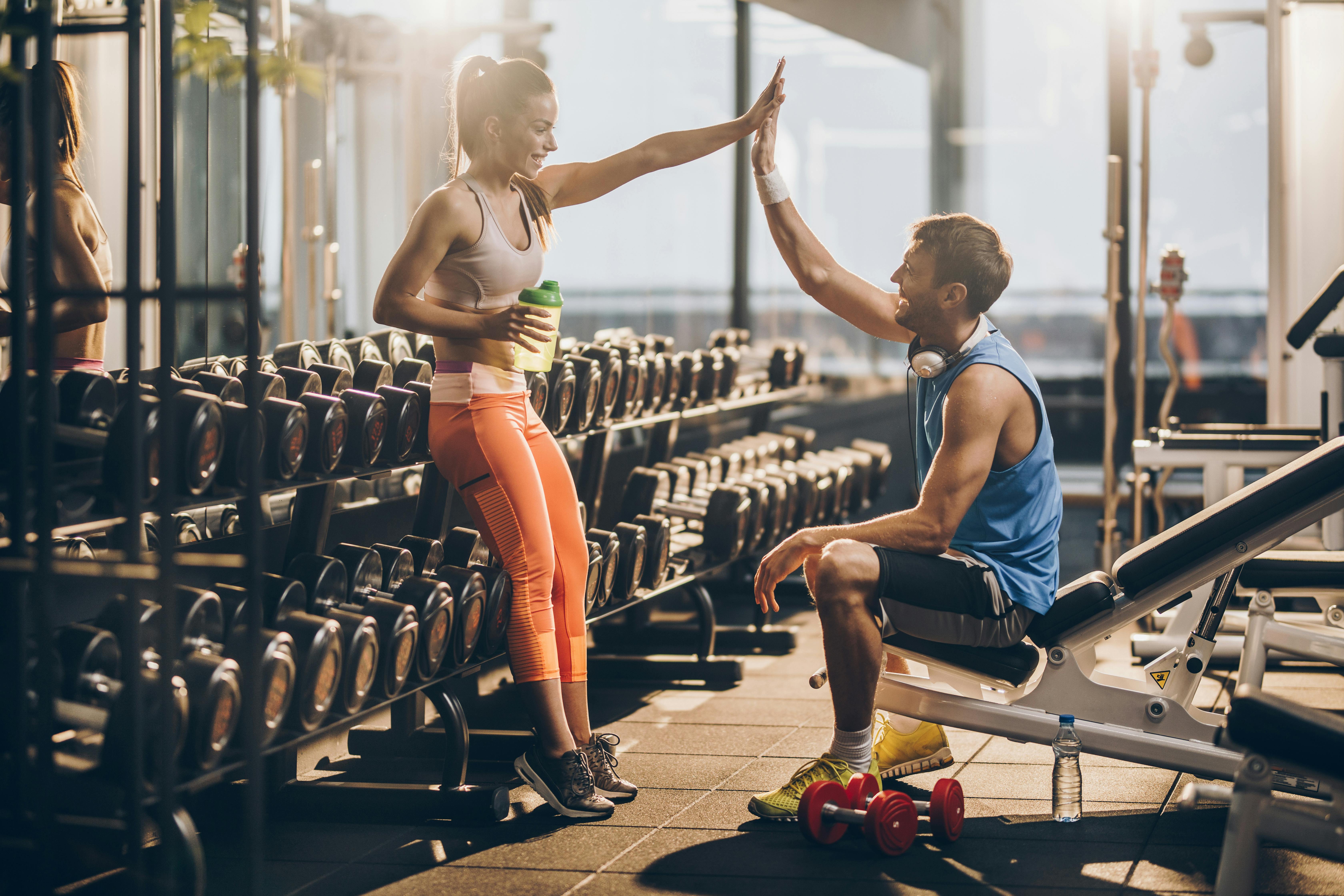 Mand og kvinde giver high five i fitness