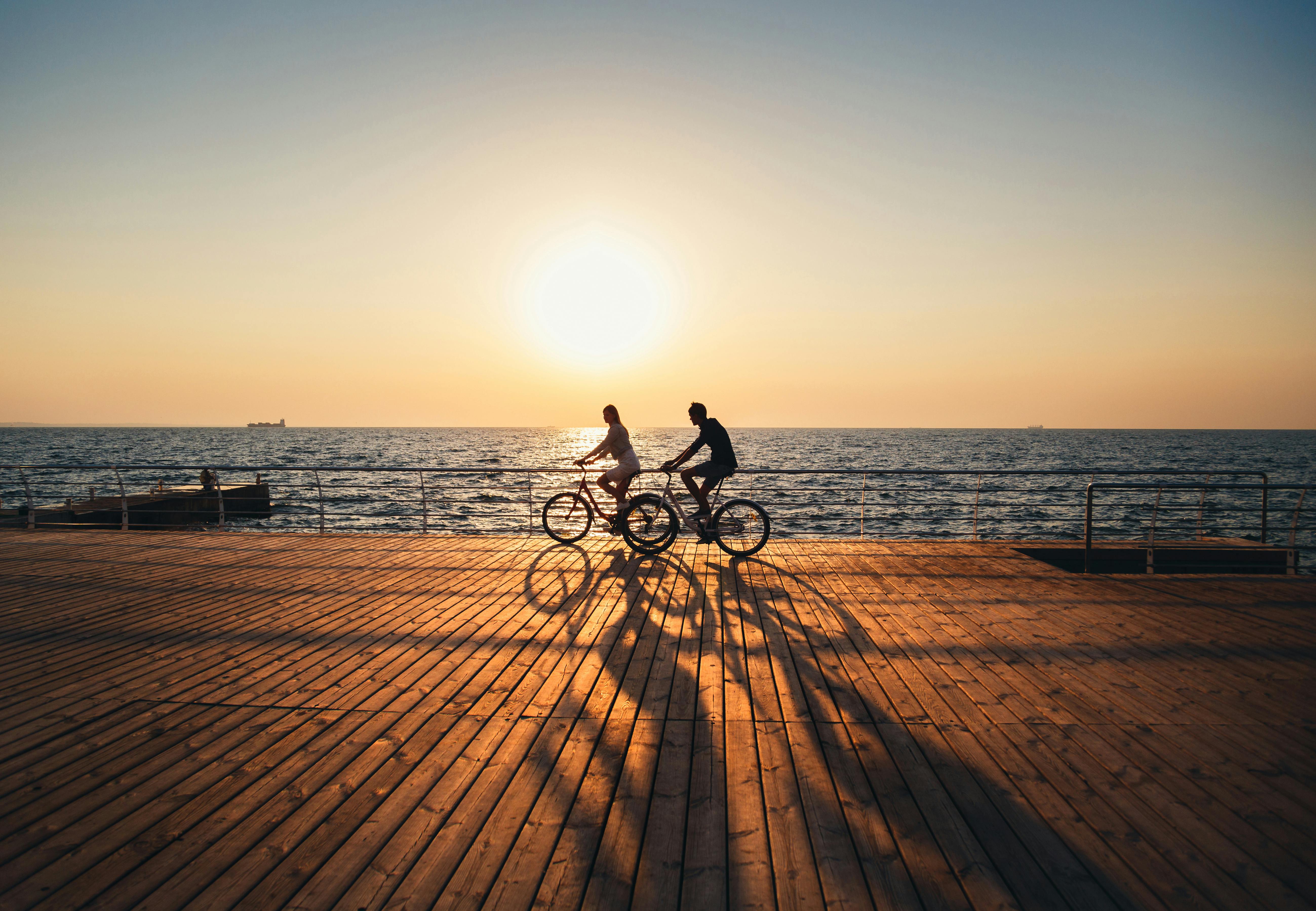 To mennesker der cykler ved solnedgang.