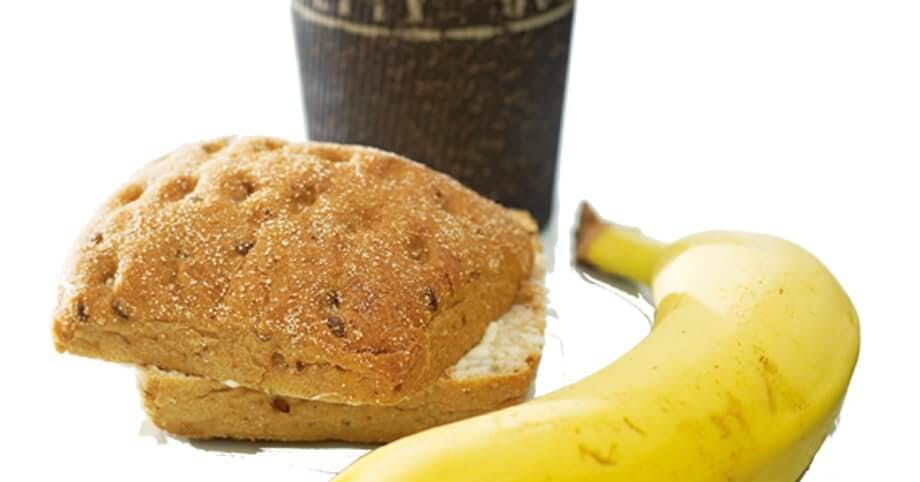 Banan, en skive grovbrød og kaffelatte.