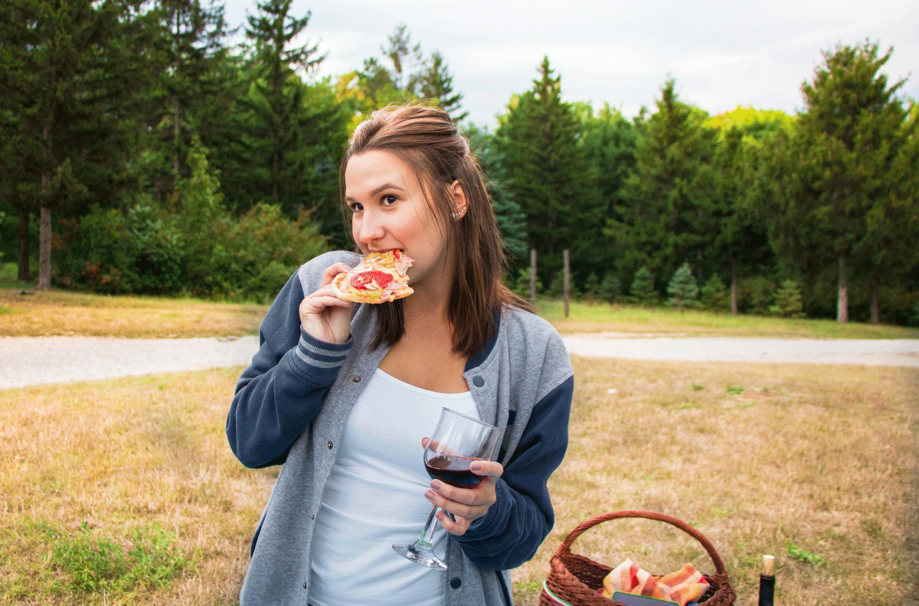Hur många kalorier? Kvinna äter pizza och dricker rödvin - kaloritabell