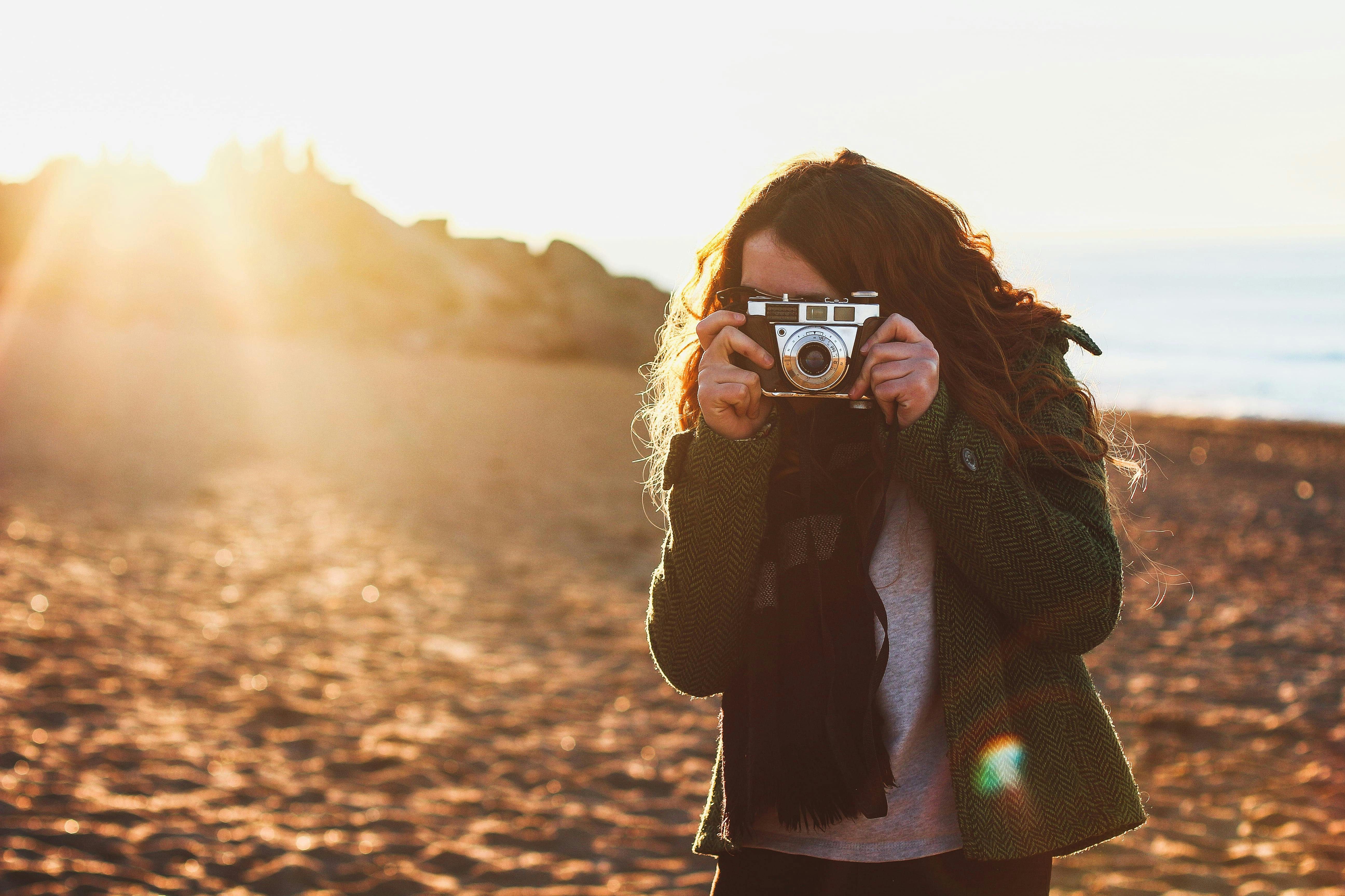 Kvinna tar bilder med analog kamera på stranden