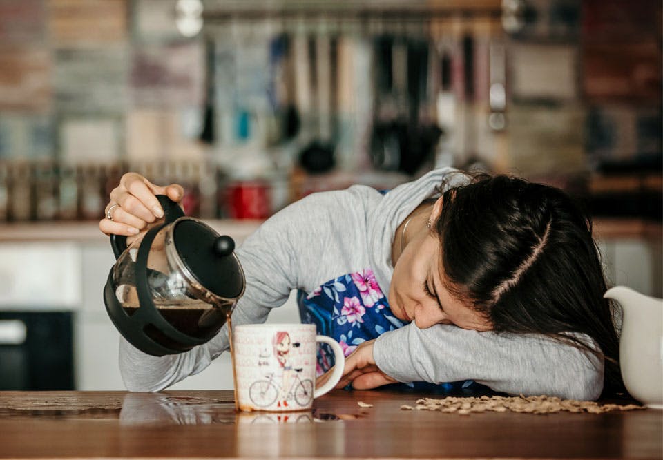 Kan du heller ikke få benene ud af sengen om morgnen? træt kvinde drikker kaffe